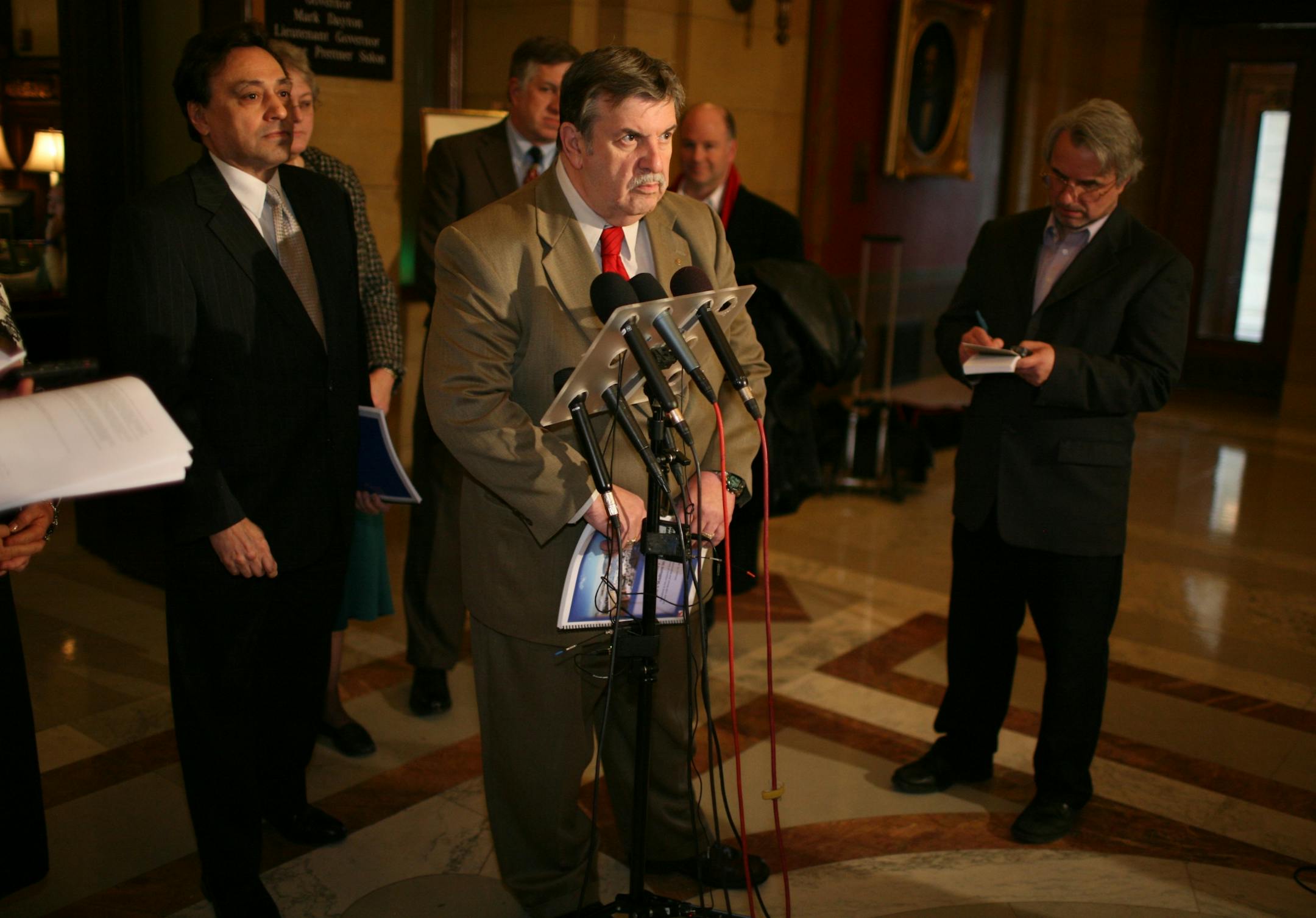 Ramsey County Commissioners Rafael Ortega, Tony Bennett and Jan Parker, accompanied by Arden Hills Mayor David Grant and St. Paul Area Chamber of Commerce President Matt Kramer, delivered to the governor's office Ramsey County's updated proposal to develop a multi-purpose stadium at the TCAAP site in Arden Hills Thursday afternoon. IN THIS PHOTO, Tony Bennett speaks at the microphones, Rafael Ortega is at left in dark suit.