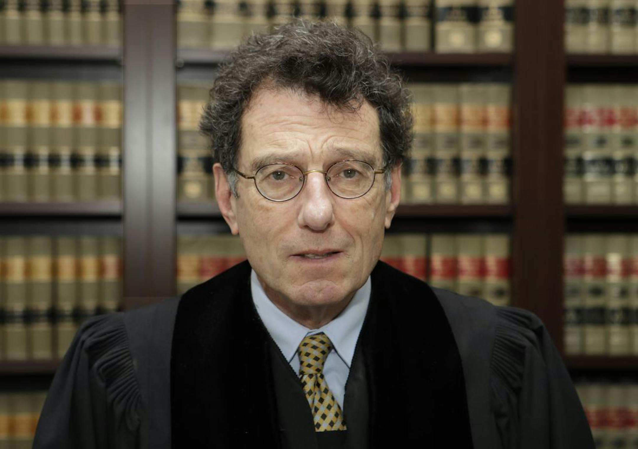 FILE - This Jan. 11, 2018 file photo shows Judge Dan Polster in his office, in Cleveland. Attorneys representing eight drug distributors, pharmacies and retailers facing trial for their roles in the national opioid crisis are seeking to disqualify the federal judge overseeing their cases saying he's shown clear bias in his efforts to obtain a multi-billion dollar global settlement. The motion was filed late Friday, Sept. 13, 2019, in U.S. District Court in Cleveland, where Judge Dan Polster pres