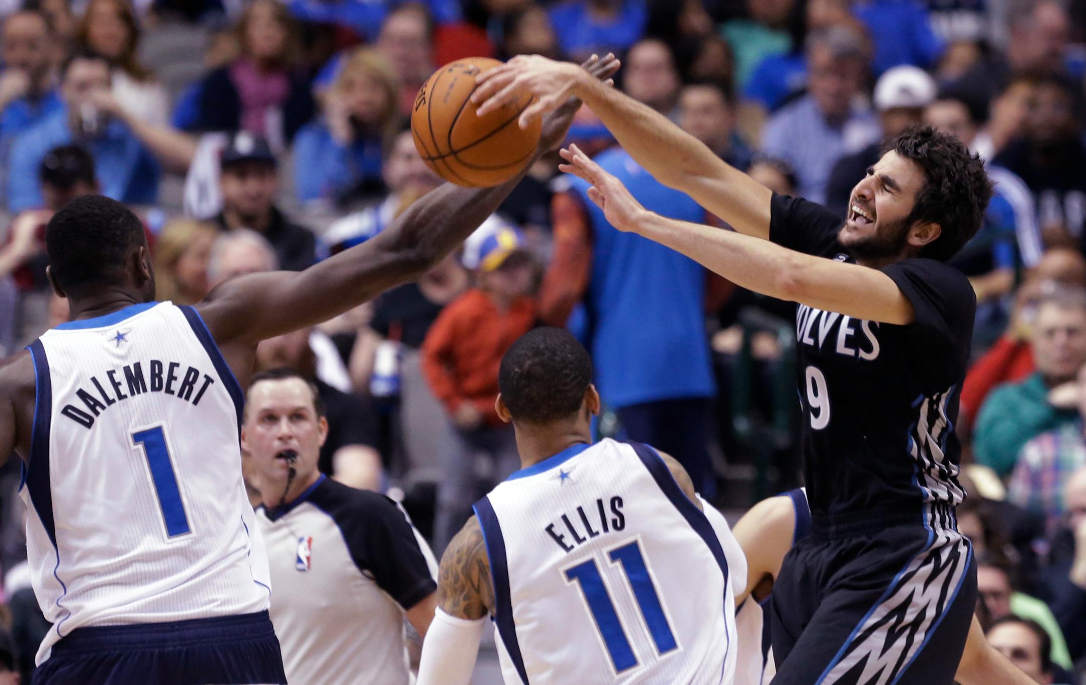 Minnesota Timberwolves guard Ricky Rubio (9) of Spain is fouled by Dallas Mavericks center Samuel Dalembert (1) as Monta Ellis (11) looks on during the first half an NBA basketball game Wednesday, March 19, 2014, in Dallas. (AP Photo/LM Otero)