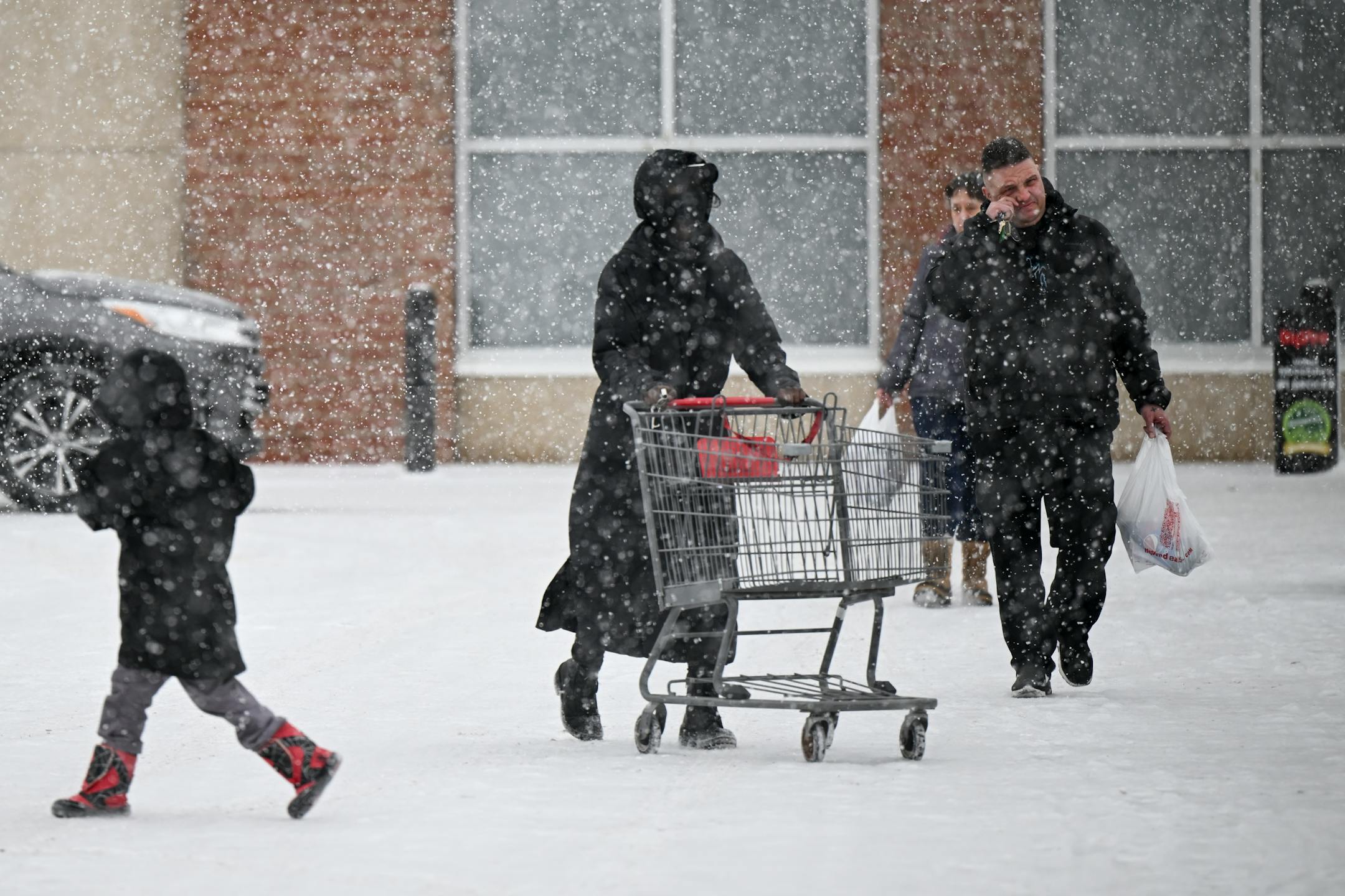 Shoppers walk back to their car in a snowstorm Tuesday, outside Hy-Vee in Robbinsdale.