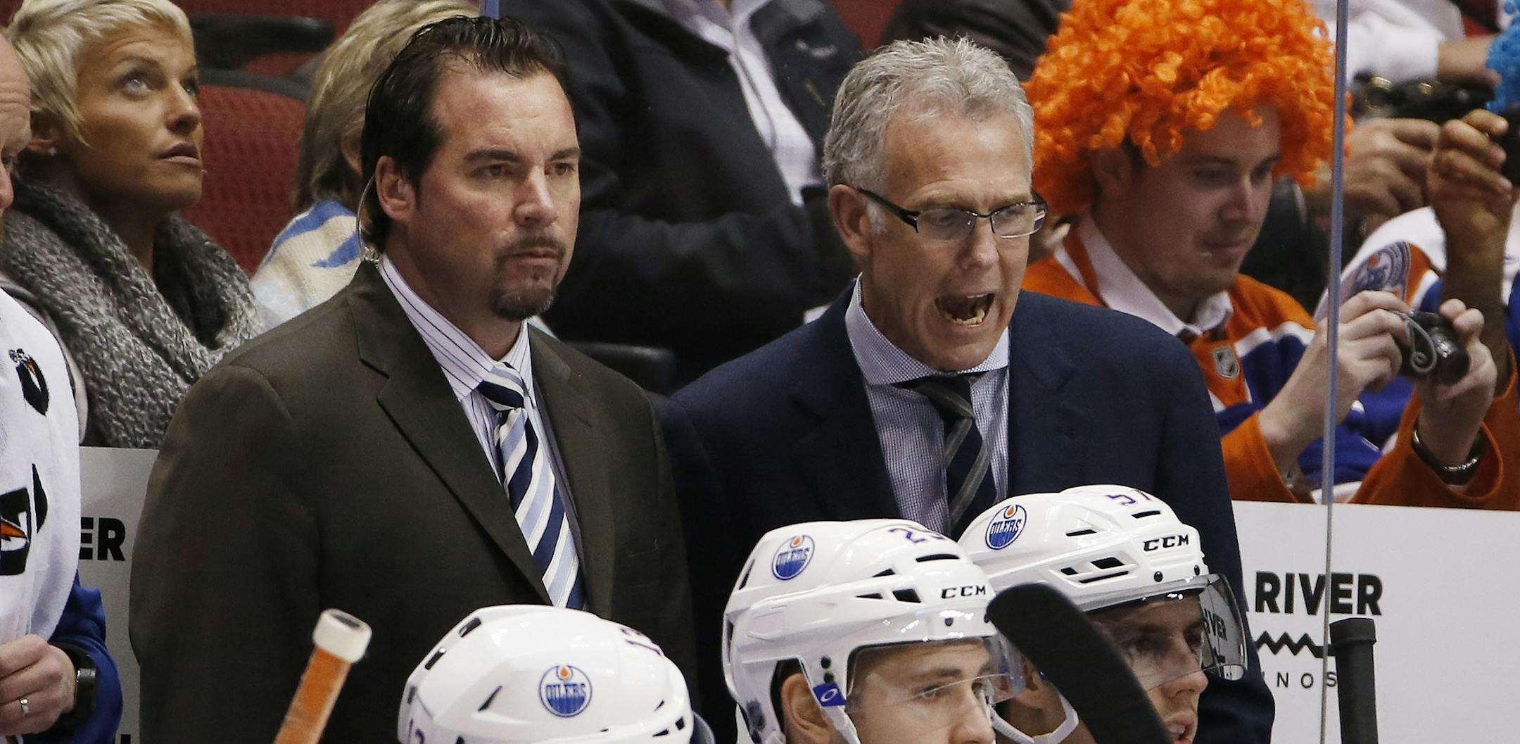 Edmonton Oilers general manager Craig MacTavish, right, shouts instructions to Oilers players as soon-to-be interim head coach Todd Nelson, left, watches the action on the ice during the first period of an NHL hockey game against the Arizona Coyotes Tuesday, Dec. 16, 2014, in Glendale, Ariz. MacTavish will take over on a transitional basis before handing the reins to interim coach Todd Nelson, who becomes the team's fifth head coach in seven years. (AP Photo/Ross D. Franklin)