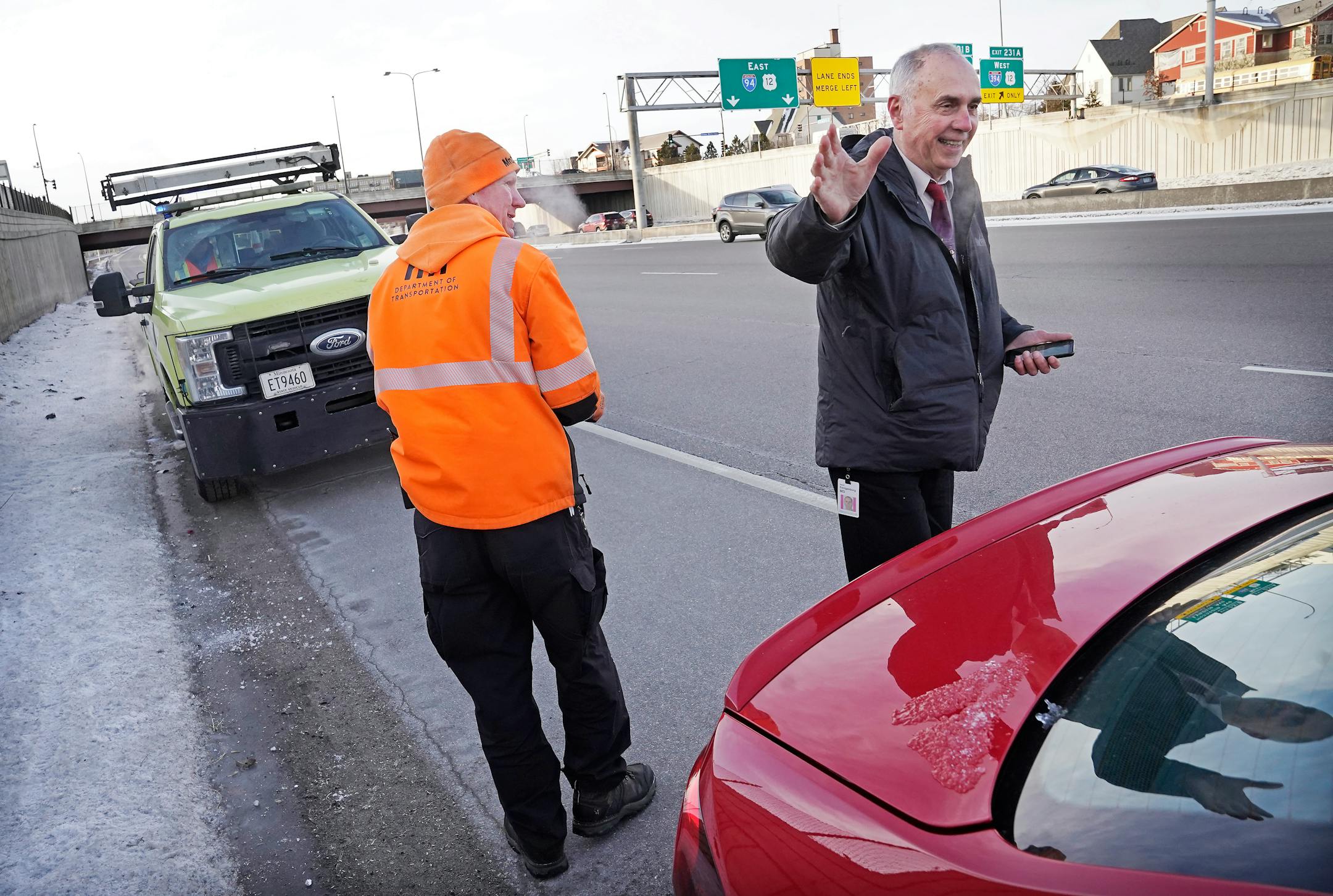 Mike Ahlman, MnDOT's Freeway Incident Response Safety Team driver, walks back to his vehicle after changing a tire for stranded physician Dr. David Eenigenburg, right, who had gotten a flat tire along I-94 and was running late for his morning appointments.