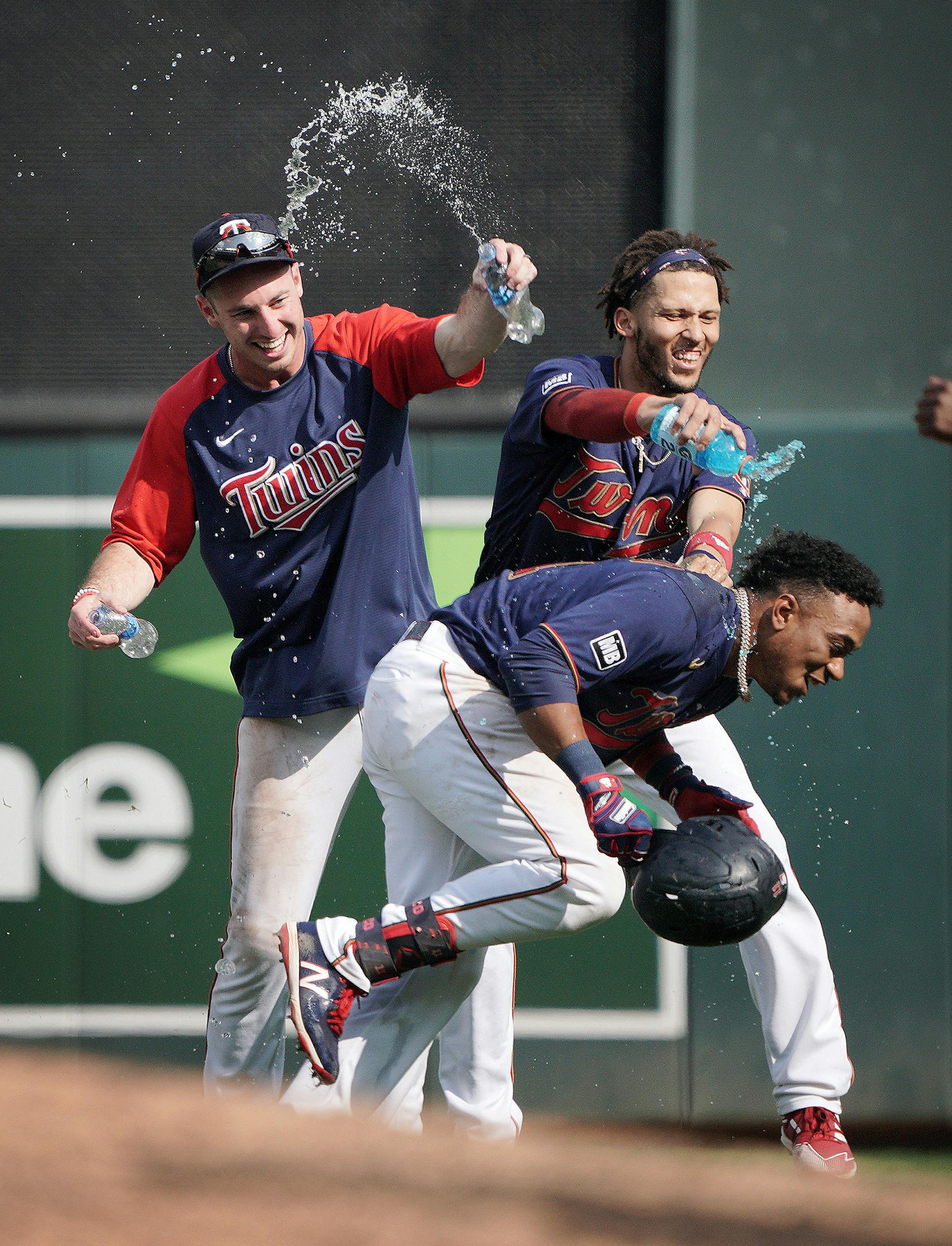 Minnesota Twins' Jorge Polanco, bottom, tries to evade a water shower after his bases-loaded, walk off single drove in the winning run in the 11th inning as the Twins beat the Cleveland Indians 8-7.