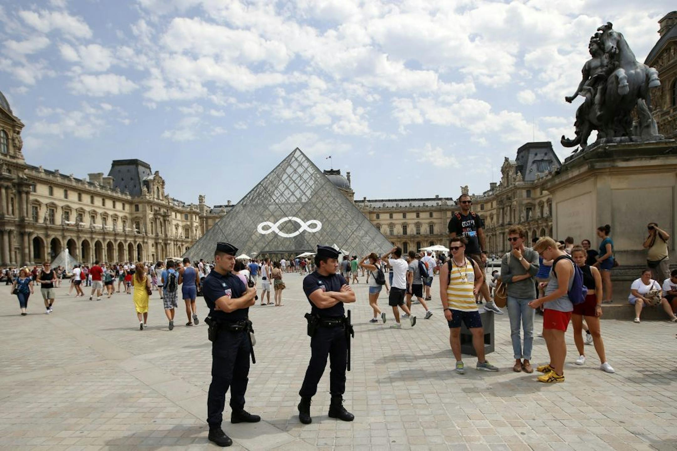 French Police Officers stand guard at the Louvre Museum during a visit of French Interior Minister Manuel Valls, unseen, in Paris Friday Aug. 2, 2013 during a tour focused on security at the city's top tourist areas.