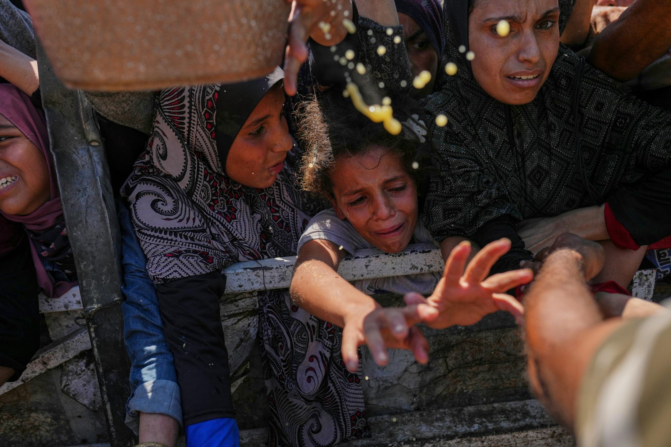 Palestinians struggle to get donated food at a community kitchen in Gaza City, northern Gaza Strip, Monday, Aug. 4, 2025