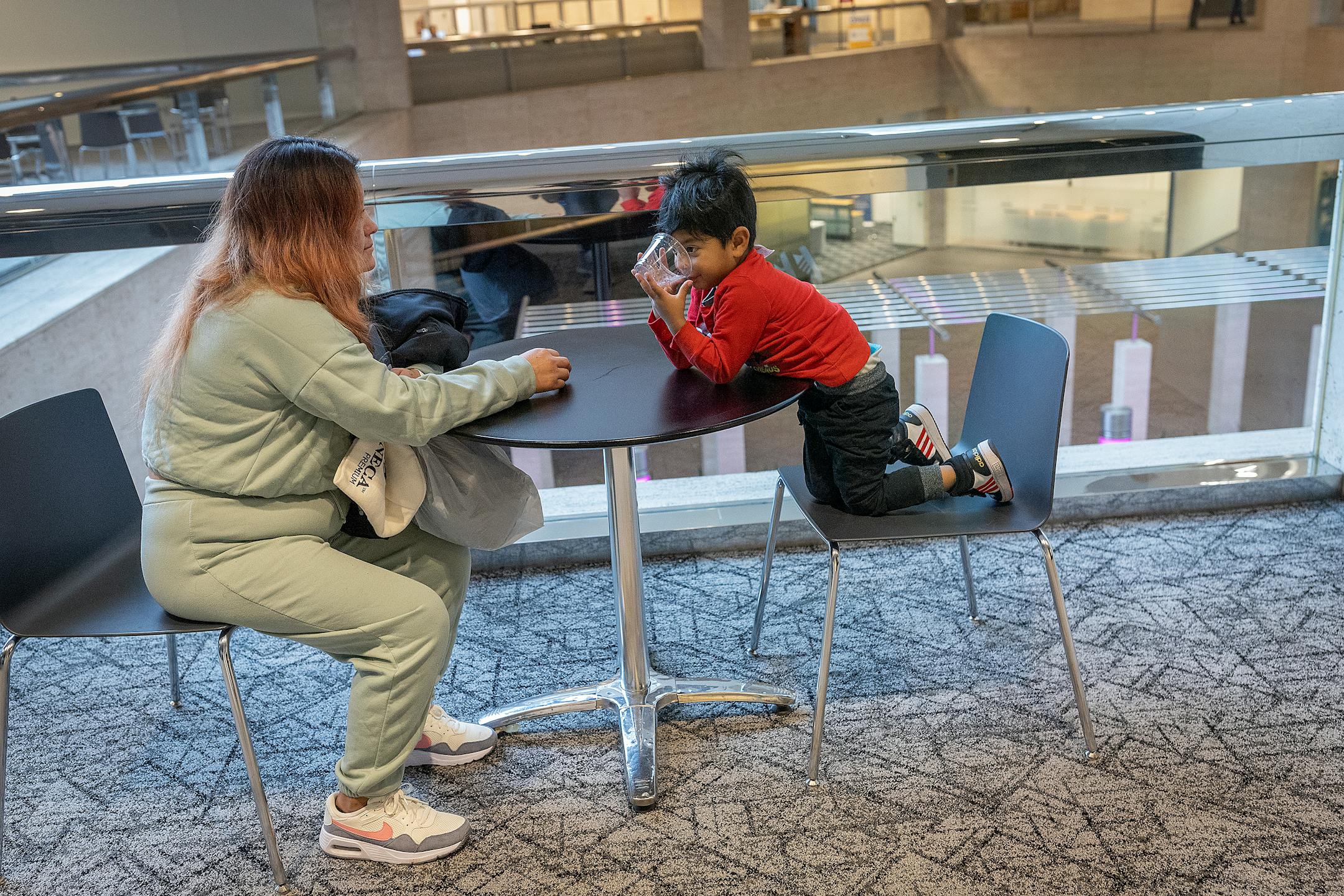 Sara takes a break with her son as she and her husband Jhon learn to navigate the skyways near their family shelter, in Minneapolis on Wednesday, Oct. 25.