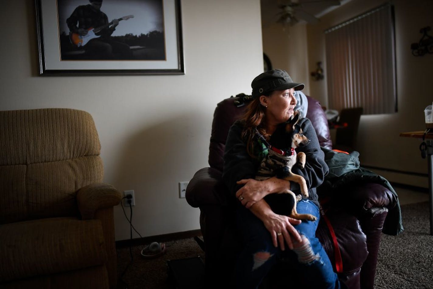 Kristine Brown looked on while holding her 6-month old puppy, Harley, in her living room Saturday. She's one of the dozens of tenants facing eviction from their apartment building in Osseo.