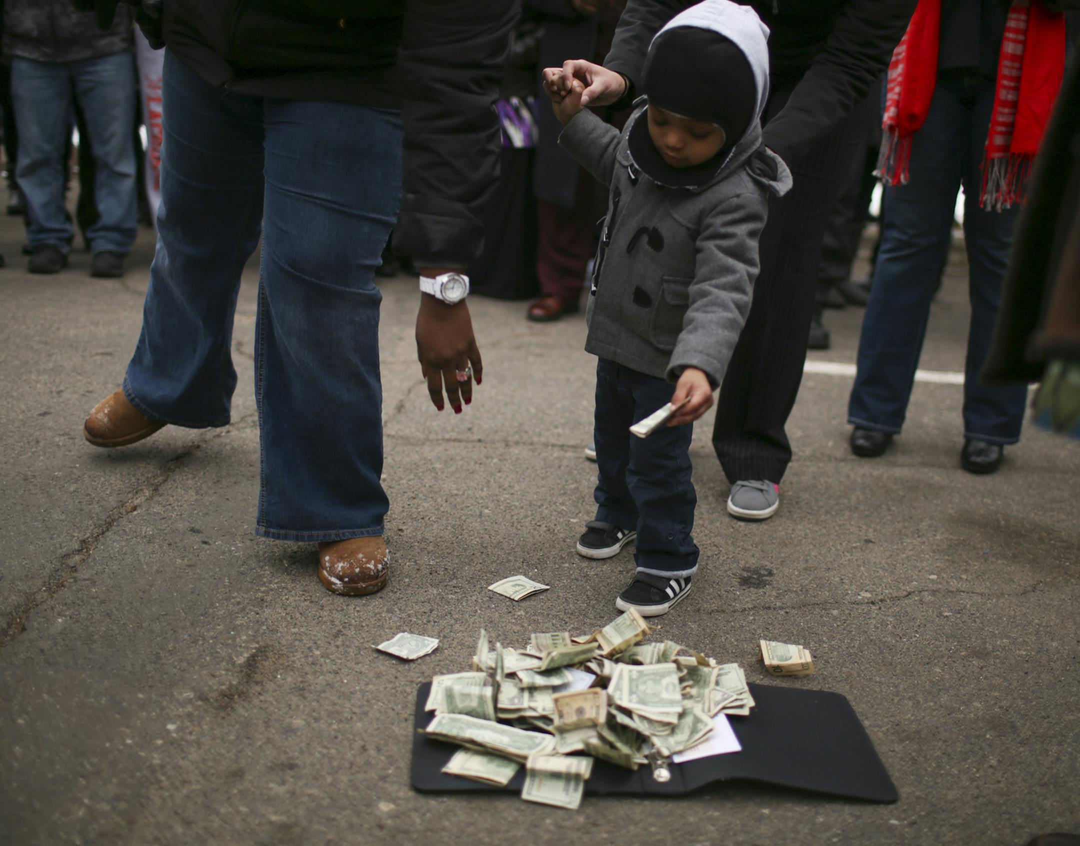 A young boy added a donation for Barway Collins' family to the pile during the vigil Monday afternoon in Crystal. ] JEFF WHEELER ï jeff.wheeler@startribune.com Family, friends, neighbors and members of the Liberian community gathered in the parking lot of the apartment complex in Crystal where his family lives to hold a prayer vigil for Barway Collins, the 10-year-old boy who has been missing since Wednesday.