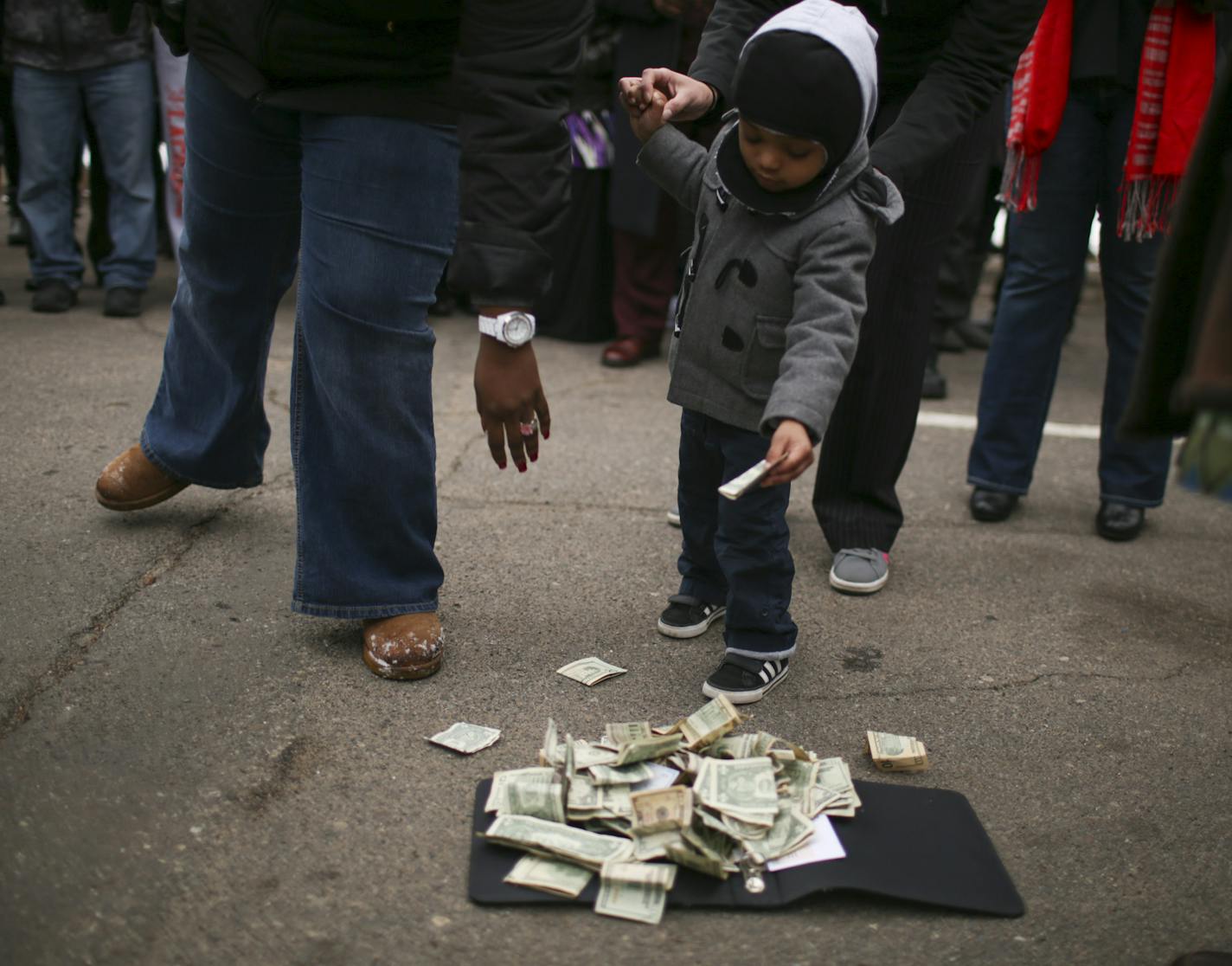 A young boy added a donation for Barway Collins' family to the pile during the vigil Monday afternoon in Crystal. ] JEFF WHEELER &#xef; jeff.wheeler@startribune.com Family, friends, neighbors and members of the Liberian community gathered in the parking lot of the apartment complex in Crystal where his family lives to hold a prayer vigil for Barway Collins, the 10-year-old boy who has been missing since Wednesday.