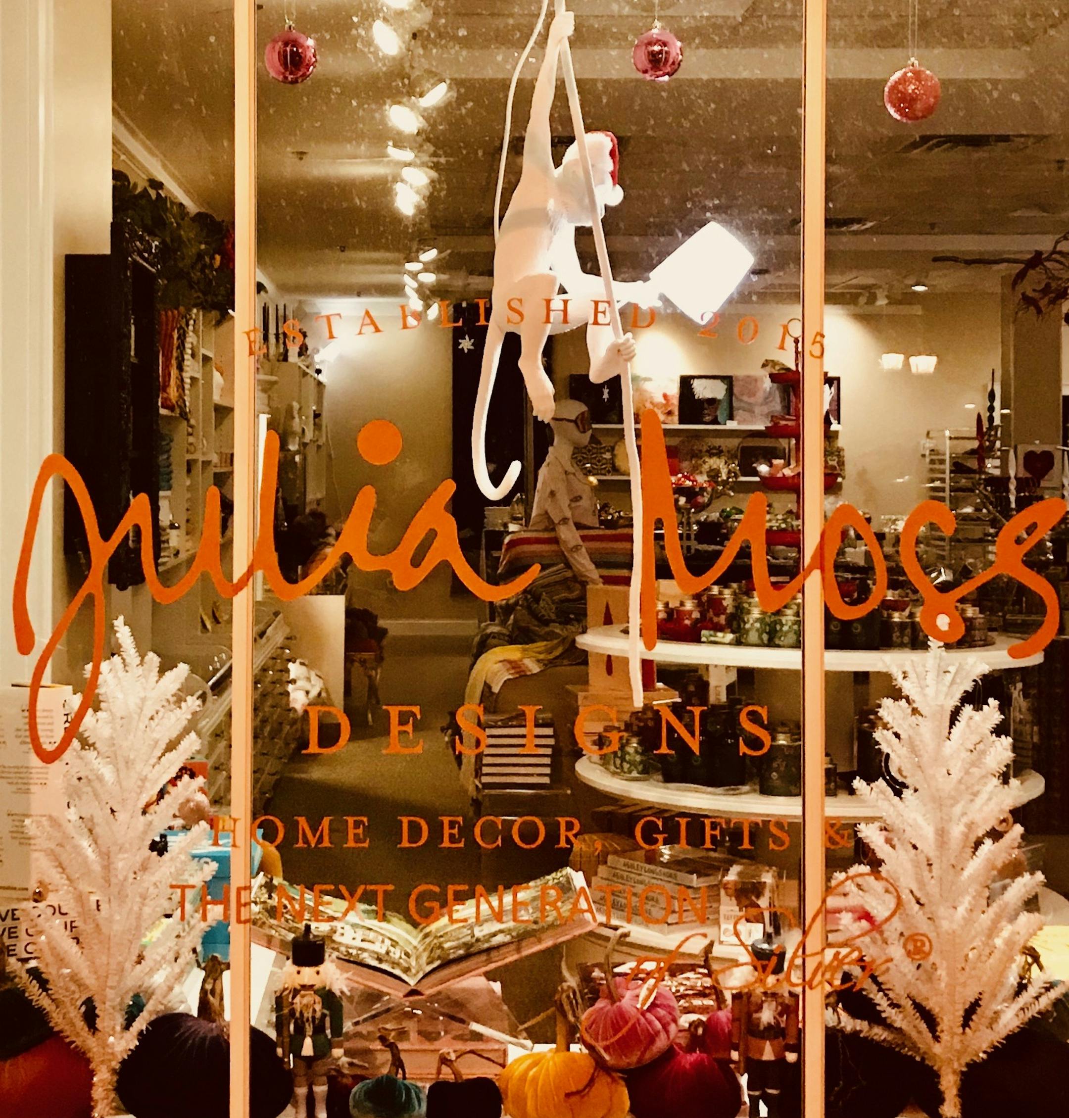 A white monkey dangles behind the window at Julia Moss Designs in Wayzata