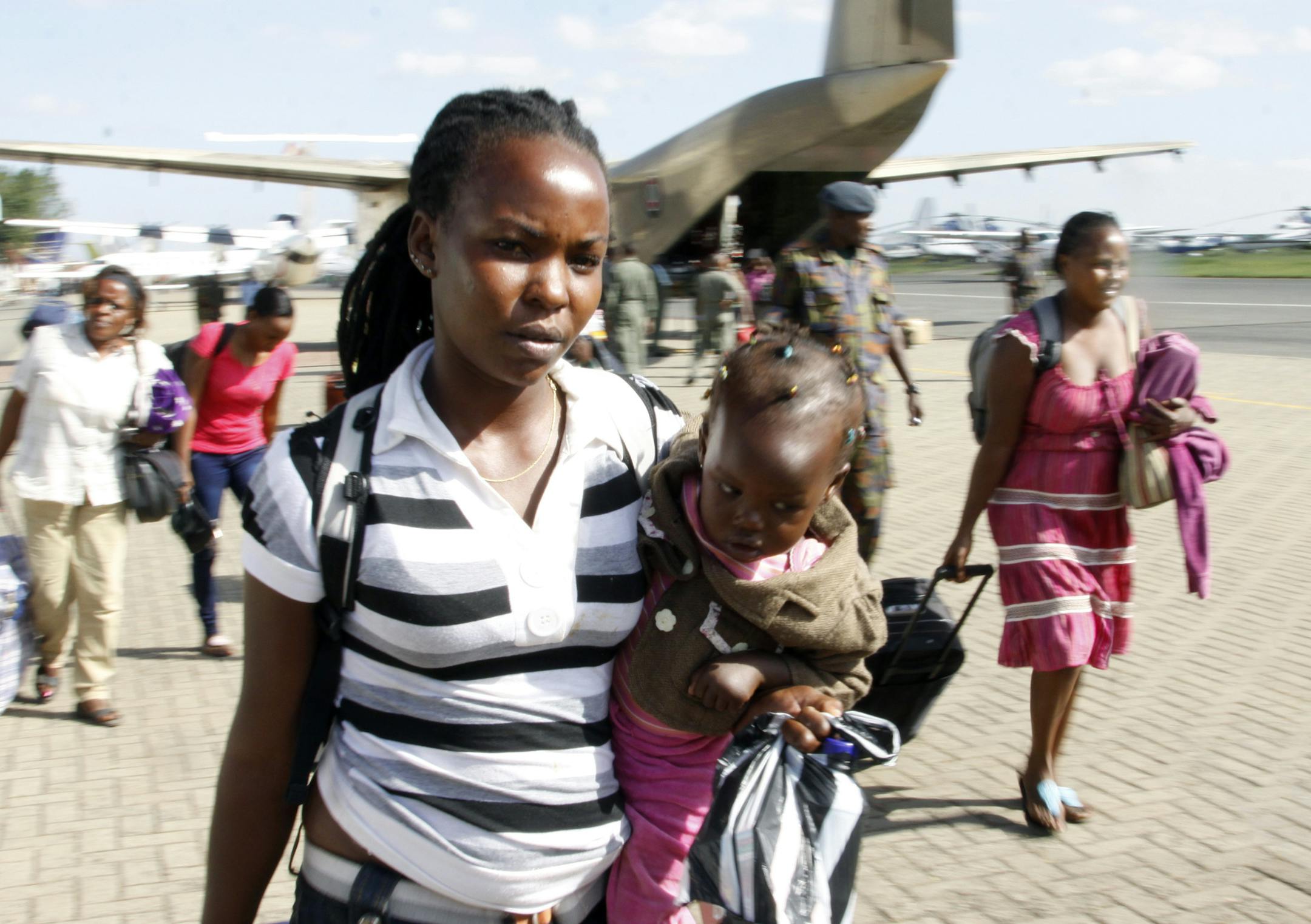 A relieved Kenyan woman carries her baby after being evacuated from South Sudan by the Kenya Defence Forces at Wilson Airport in Nairobi, Kenya, Tuesday, Dec. 24, 2013. More than 1000 Kenyans are still stranded in Africa's youngest state that is on the verge of civil war. South Sudan's military spokesman says there is increasing tension at a United Nations camp in the rebel-held city of Bor because armed elements have entered the congested area where the U.N. says about 17,000 civilians are seek