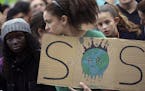 A young demonstrator holds a sign outside the Portuguese parliament in Lisbon during a worldwide protest demanding action on climate change, Friday, N