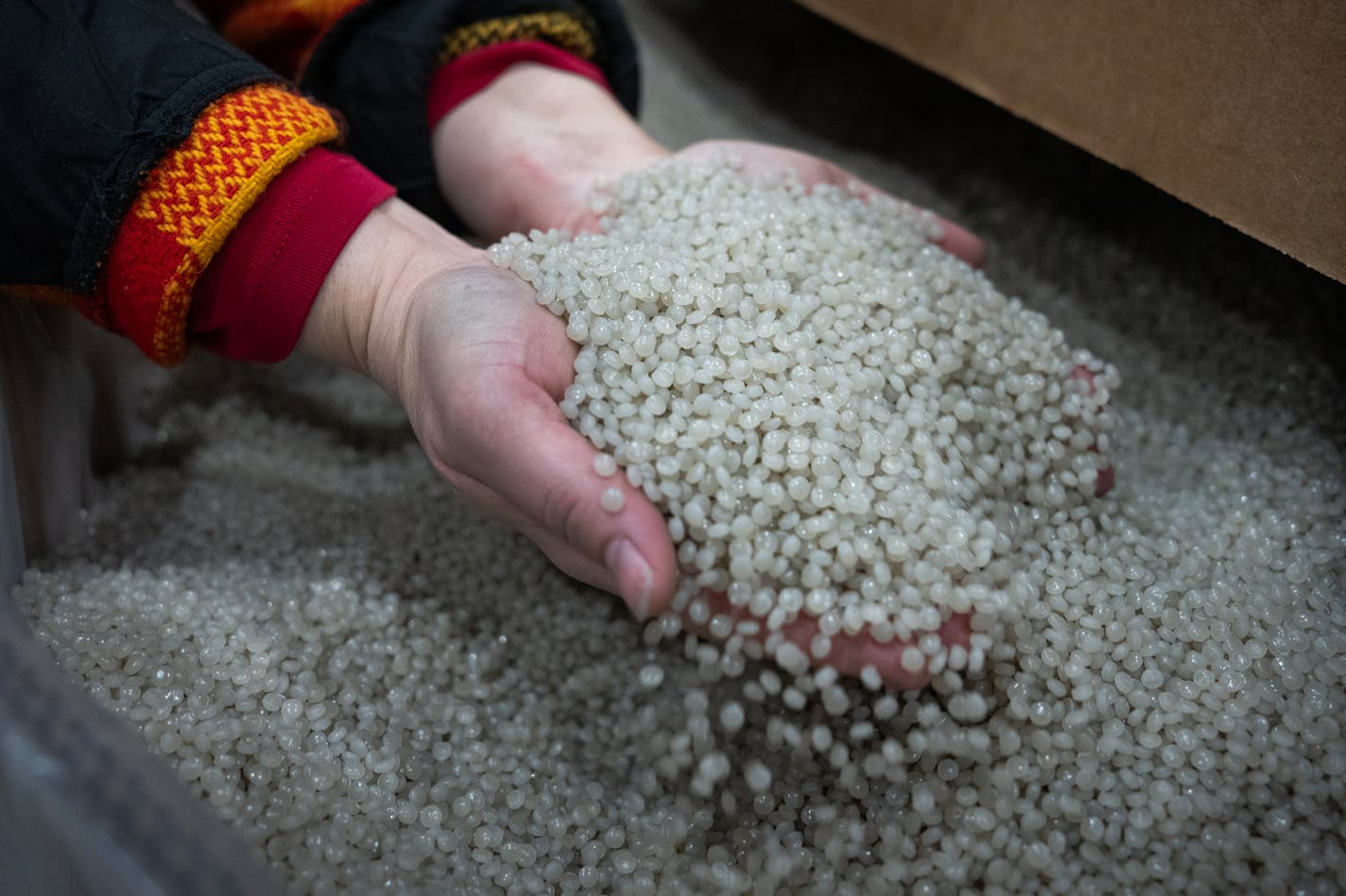 Cathy Wells, executive assistant, handles the final product in a 1,000 pound container inside the Myplas USA plastic recycling facility in Rogers, Minn., on Tuesday, Dec. 12, 2023.