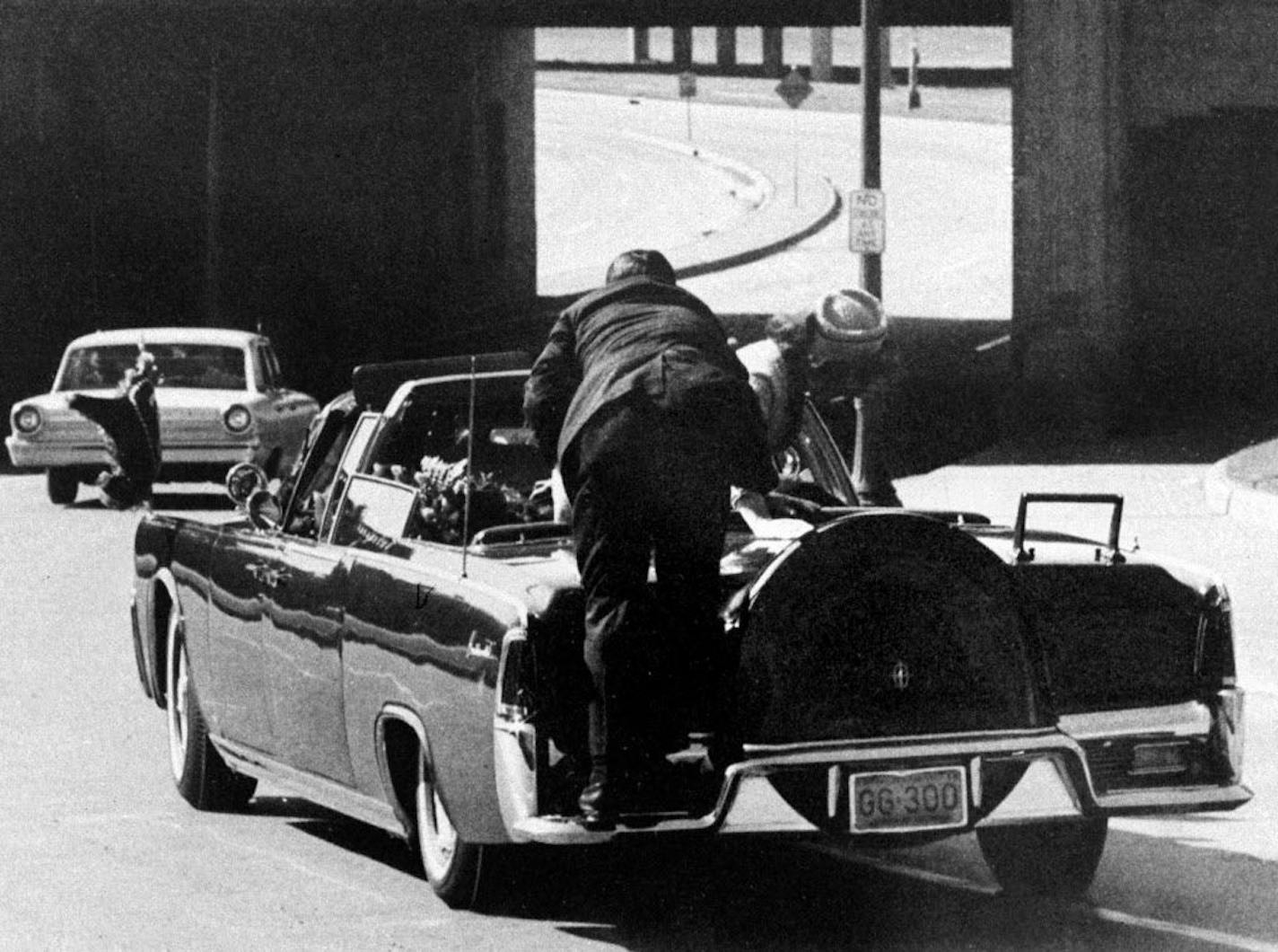 FILE - In this Friday, Nov. 22, 1963 file photo, President John F. Kennedy slumps down in the back seat of the Presidential limousine as it speeds along Elm Street toward the Stemmons Freeway overpass in Dallas after being fatally shot. First lady Jacqueline Kennedy leans over the president as Secret Service agent Clint Hill pushes her back to her seat. "She's going to go flying off the back of the car," Hill thought as he tried to secure the first lady.