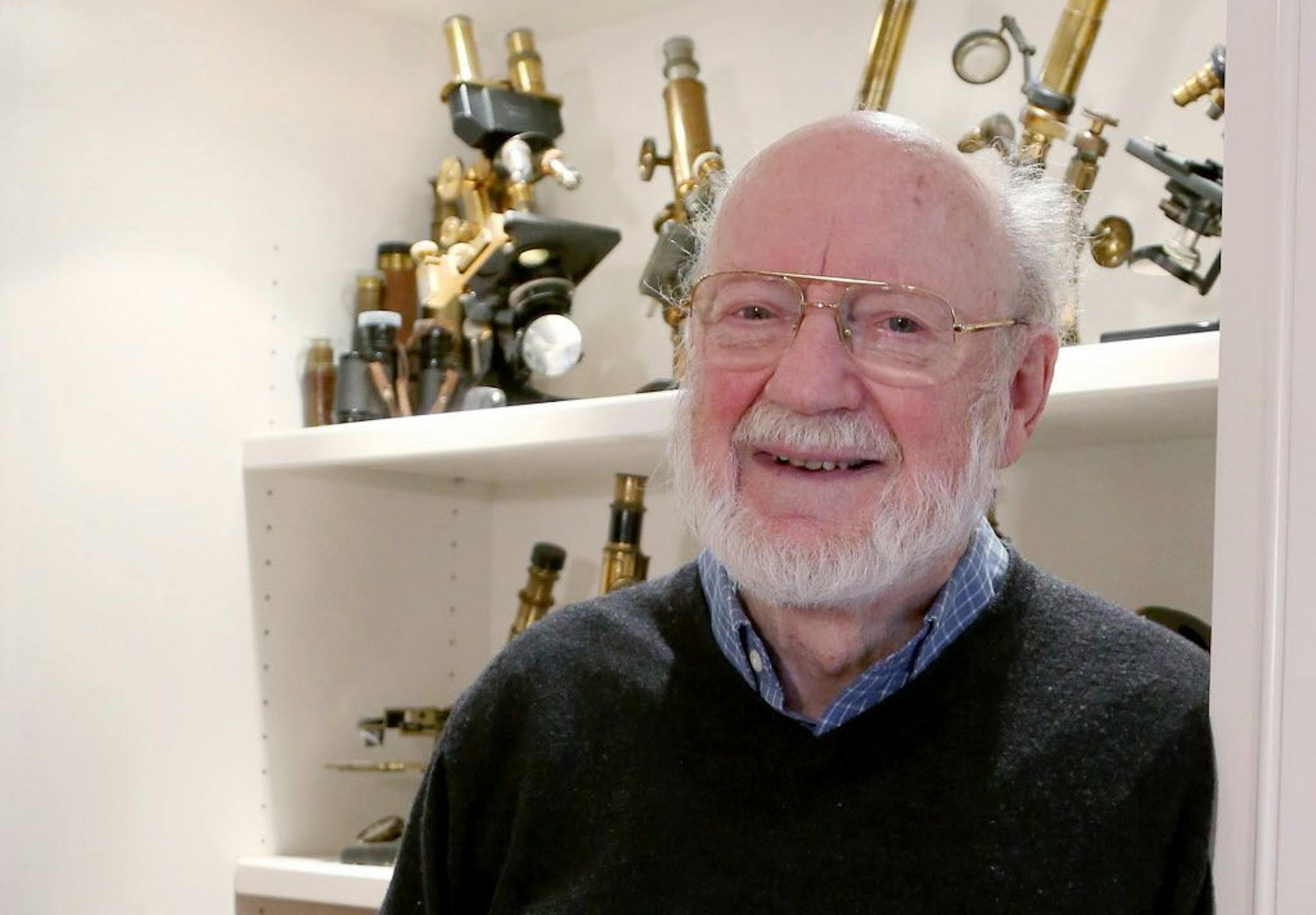 Scientist William C. Campbell poses for a photo with a collection of microscopes in his home in North Andover, Mass., Monday, Oct. 5, 2015. Campbell is one of three scientists from the U.S., Japan and China who won the Nobel Prize in medicine on Monday for discovering drugs to fight malaria and other tropical diseases that affect hundreds of millions of people every year.