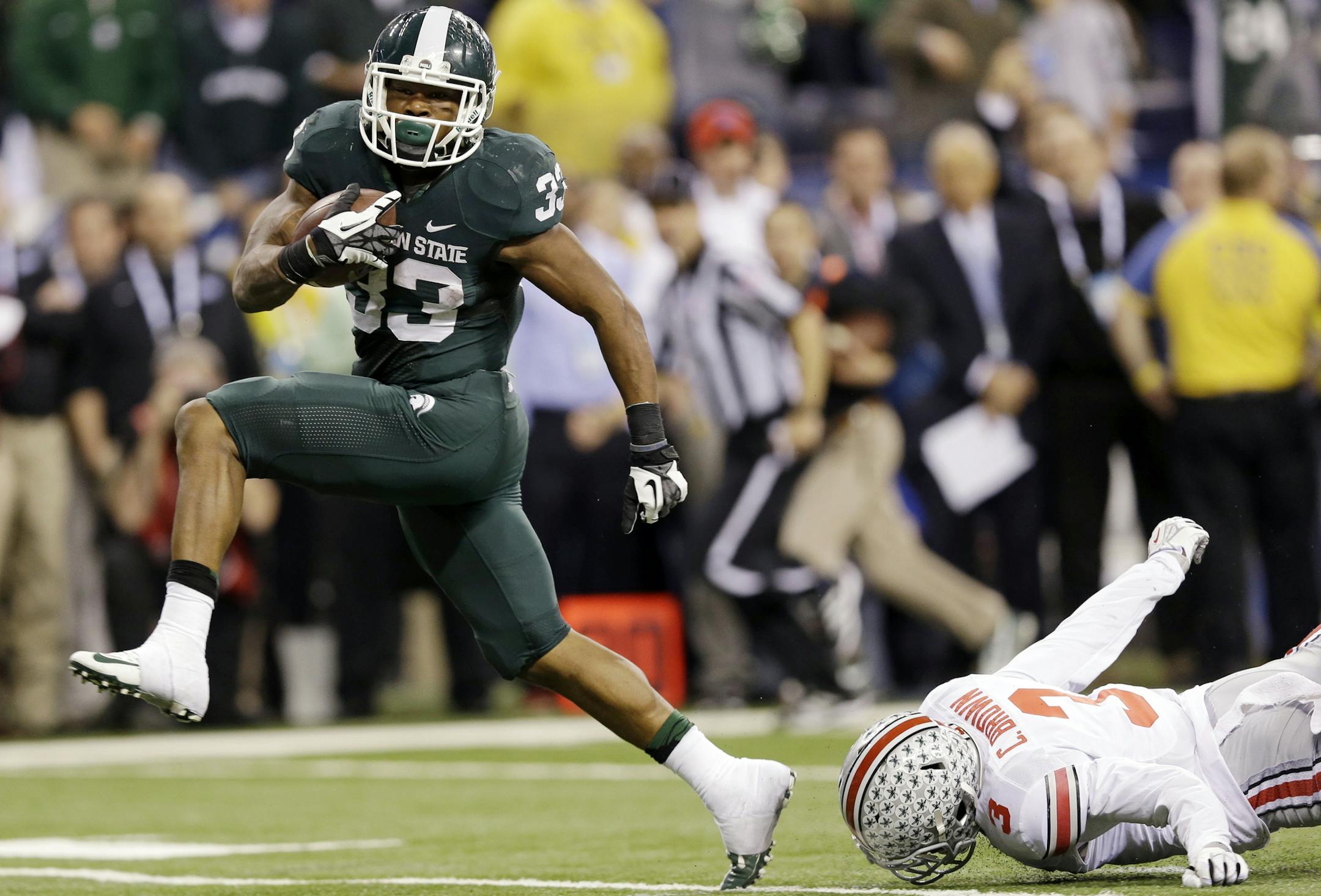 Michigan State's Jeremy Langford (33) runs out of the tackle of Ohio State's Corey Brown (3) for a 26-yard touchdown run during the fourth quarter of an Big Ten Conference championship NCAA college football game Saturday, Dec. 7, 2013, in Indianapolis. (AP Photo/Michael Conroy)