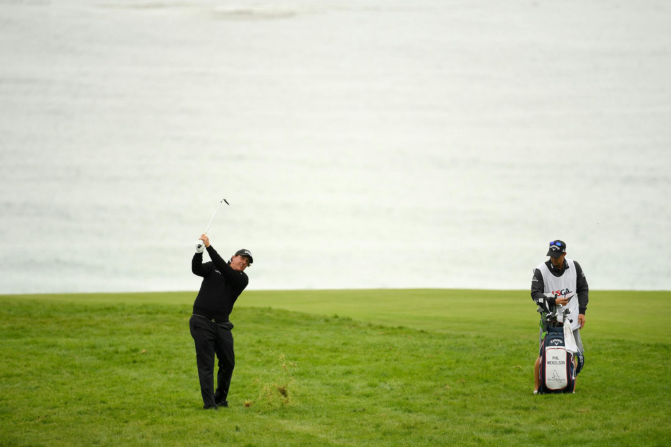 Phil Mickelson plays an approach shot on the 11th hole as his caddie looks on during the third round of the U.S. Open at Pebble Beach Golf Links on Saturday, June 15, 2019, in Pebble Beach, Calif. (Ross Kinnaird/Getty Images/TNS) **FOR USE WITH THIS STORY ONLY**