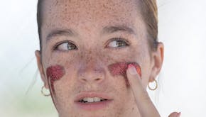 New Prague's Hailee Ullom gets prepped with eye black before the Class 4A final against Rogers.