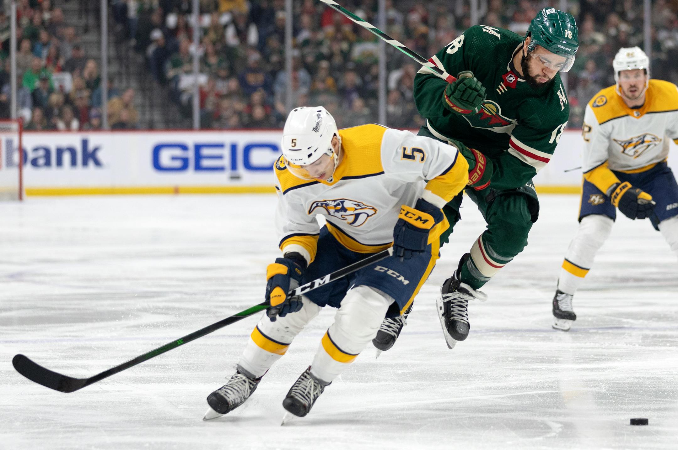 Matt Benning (5) of the Nashville Predators and Jordan Greenway (18) of the Minnesota Wild fight for the puck in the first period.