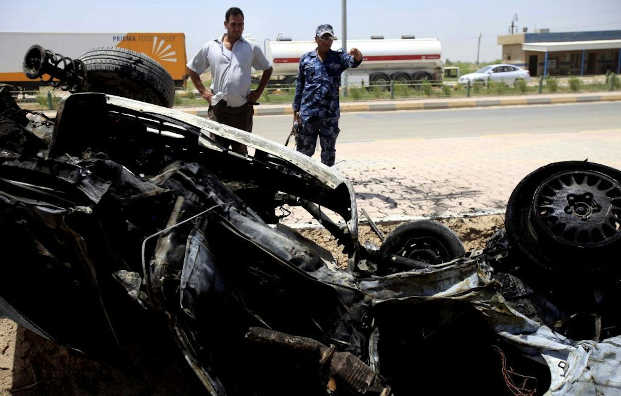 An Iraqi man and policeman inspect damages after a car bomb attack outside Kut, 100 miles (160 kilometers) southeast of Baghdad, Iraq, Sunday, June 16, 2013. Most of the car bombs hit Shiite-majority areas and were the cause of most of the casualties, killing tens. The blasts hit half a dozen cities and towns in the south and center of the country.