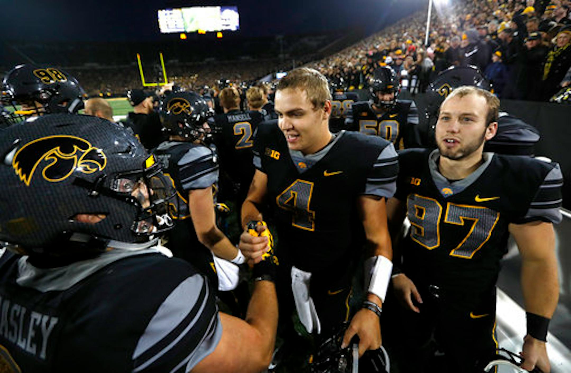 Iowa quarterback Nathan Stanley (4) and Tyler Kluver, right, celebrate with teammate Nick Easley, left, after an NCAA college football game against Ohio State, Saturday, Nov. 4, 2017, in Iowa City, Iowa. (AP Photo/Charlie Neibergall)