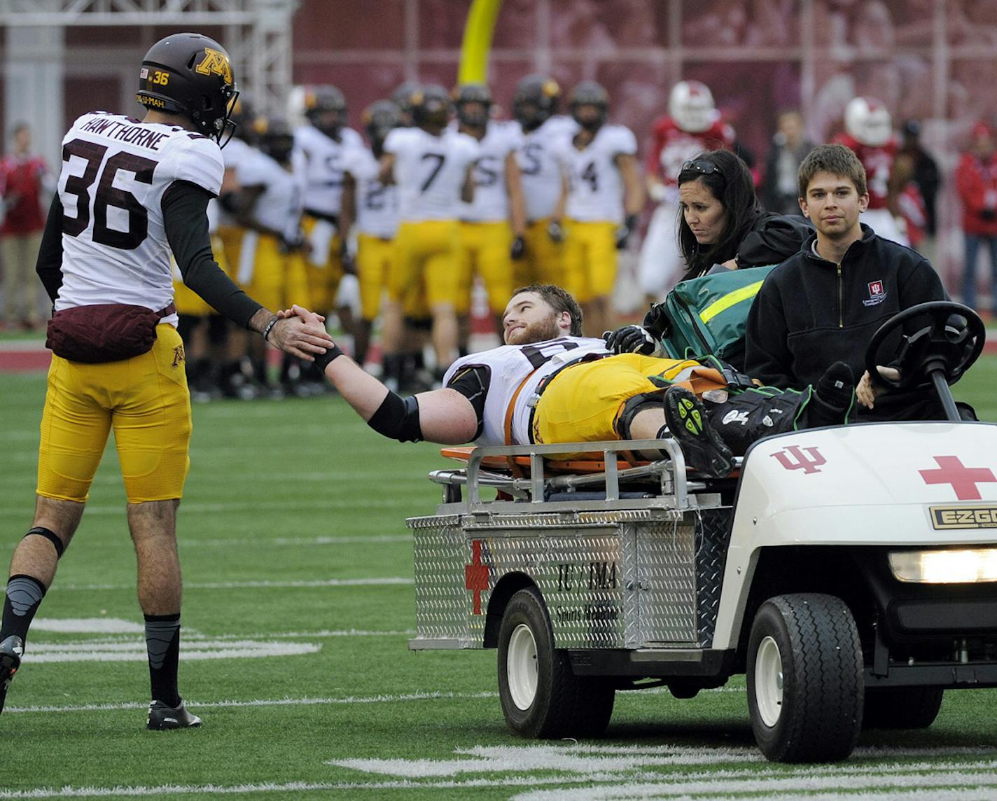 Minnesota's Chris Hawthorne, left, shakes Minnesota's Jon Christenson's hand as he is taken off the field after being injured during the first half of an NCAA college football game against Indiana in Bloomington, Ind., Saturday, Nov. 2, 2013. (AP Photo/ Alan Petersime) ORG XMIT: MIN2013110217195155