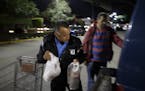 Security guard Guillermo Soria, left, helps a customer while working in front of a Smart & Final store Wednesday, Nov. 18, 2015, in Tijuana, Mexico. A