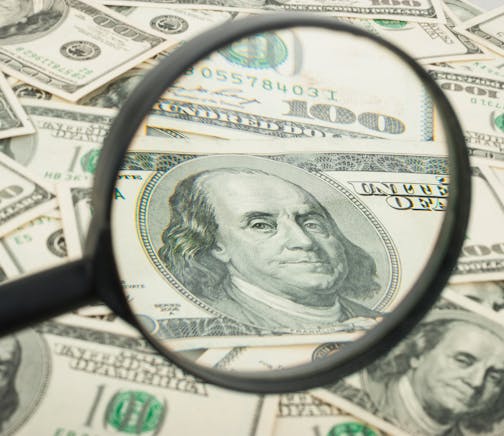 Hundred dollar banknotes under magnifying glass