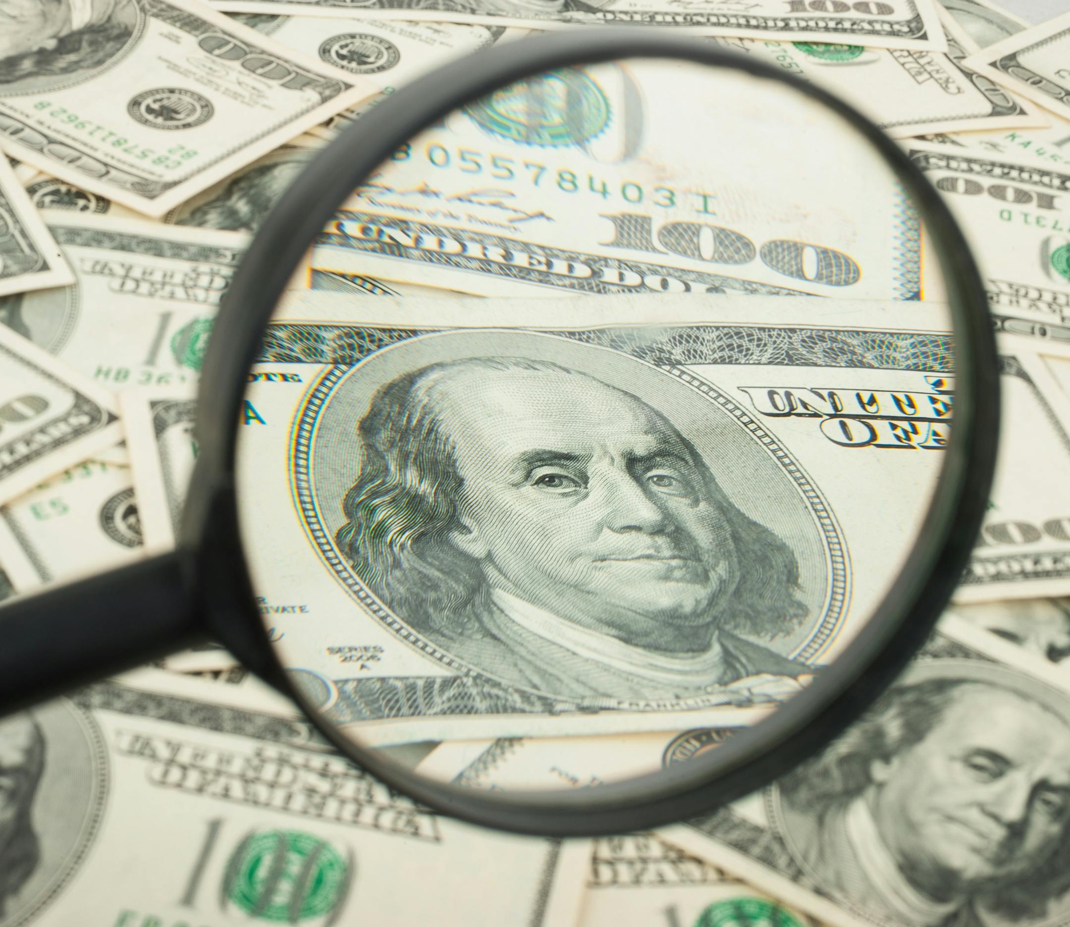 Hundred dollar banknotes under magnifying glass