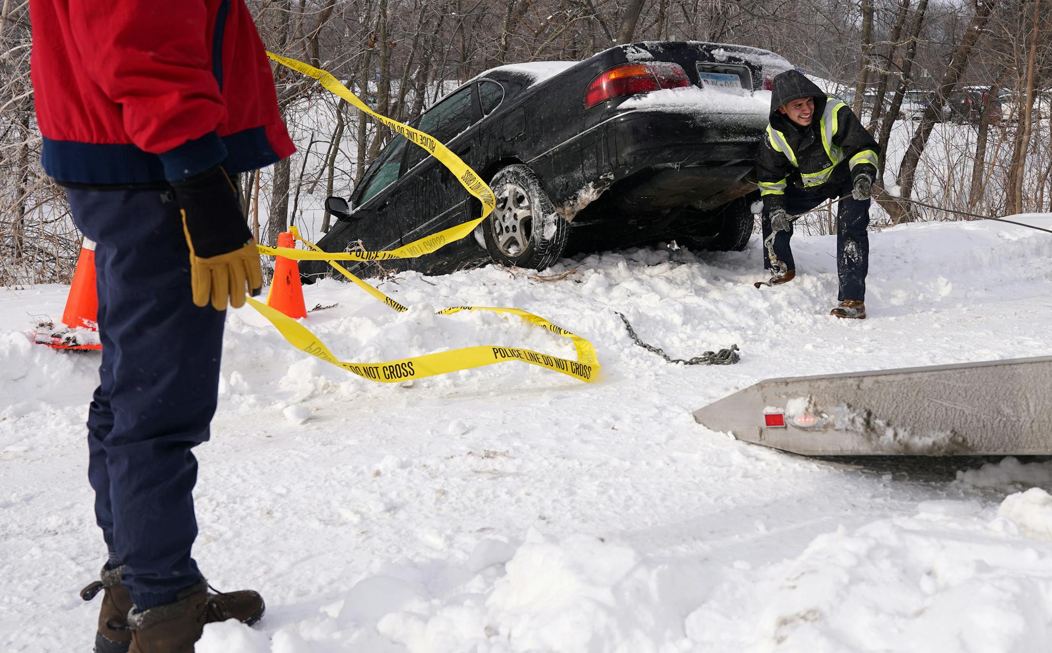 Jason Arce, a driver with Galeana's Towing, worked to pull Tyler Freed's car from a ditch Saturday morning after it skidded off the road on an ice patch during Friday night's snowstorm near the Lake Harriet Bandshell. Freed wasn't injured in the incident and passing motorists gave him a ride home until he was able to get a tow in the morning.