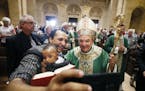Aime held his son Raphael as they took a selfie with Archbishop Bernard Hebda who greeted parishioners after celebrating his first mass at the St. Pau