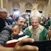 Aime held his son Raphael as they took a selfie with Archbishop Bernard Hebda who greeted parishioners after celebrating his first mass at the St. Pau