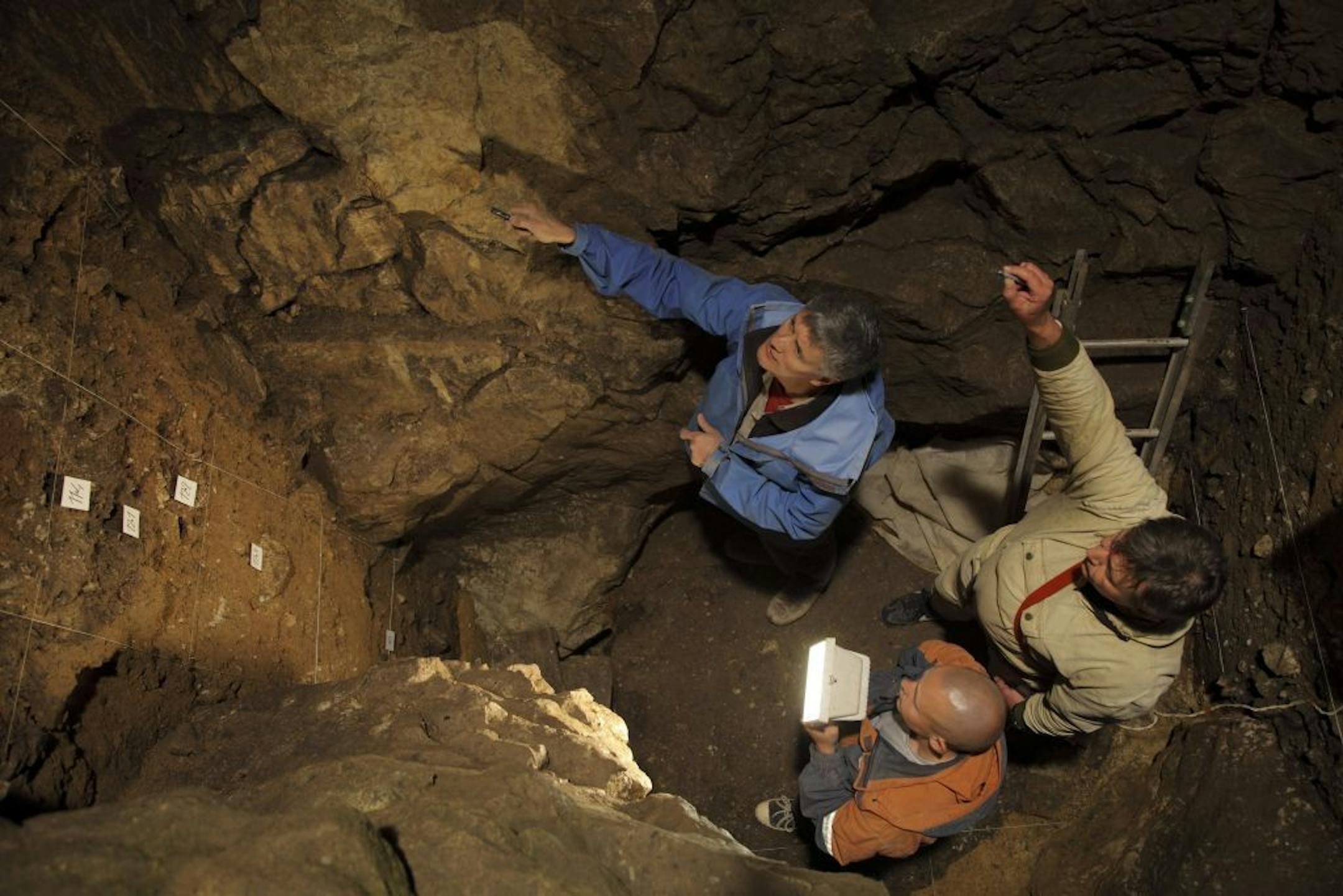 In a photo provided by Sergei Zelensky, Clockwise from top, researchers Richard Roberts, Vladimir Ulianov and Maxim Kozlikin in a chamber of the Denisova cave in Siberia, where the fossil of a 90,000-year-old human hybrid was discovered. Genetic analysis of bones discovered here hint that the prehistoric world may have been filled with "hybrid" humans. (Sergei Zelensky/Institute of Archeology and Ethnography of the Siberian Branch of the Russian Academy of Sciences via The New York Times) -- NO