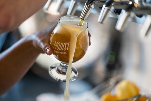 A bartender pours a beer at Modist Brewing.