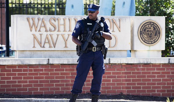 FILE - This Sept. 17, 2013 file photo shows an armed officer who said he is with the Defense Department, standing near guard the gate at the Washingto