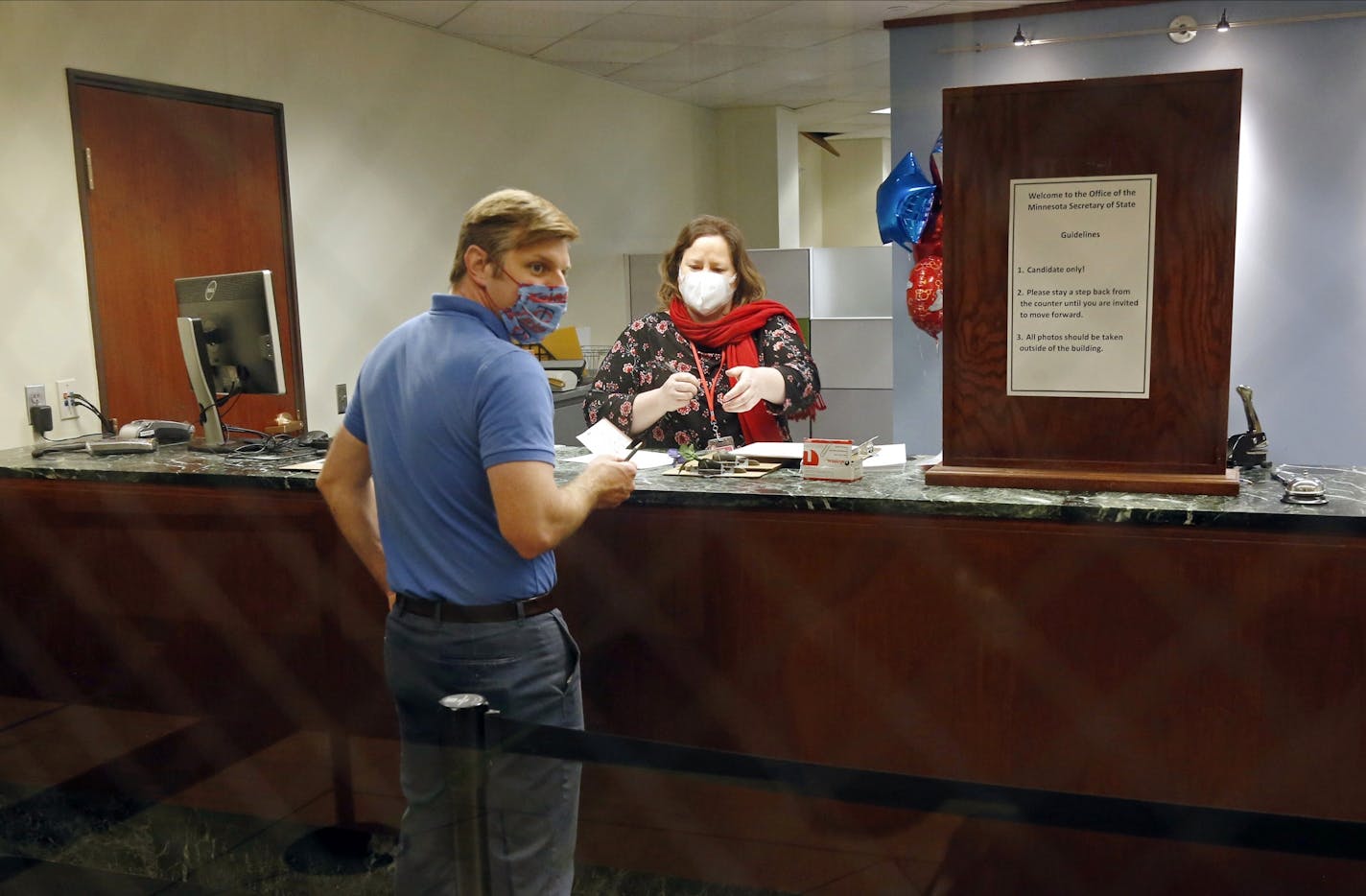 Face masks and social distancing were part of the process as election staffer Stella Hegg assists State Rep. Michael Howard as he files for re-election at the Secretary of State's Office Tuesday, May 19, 2020 in St. Paul, Minn.