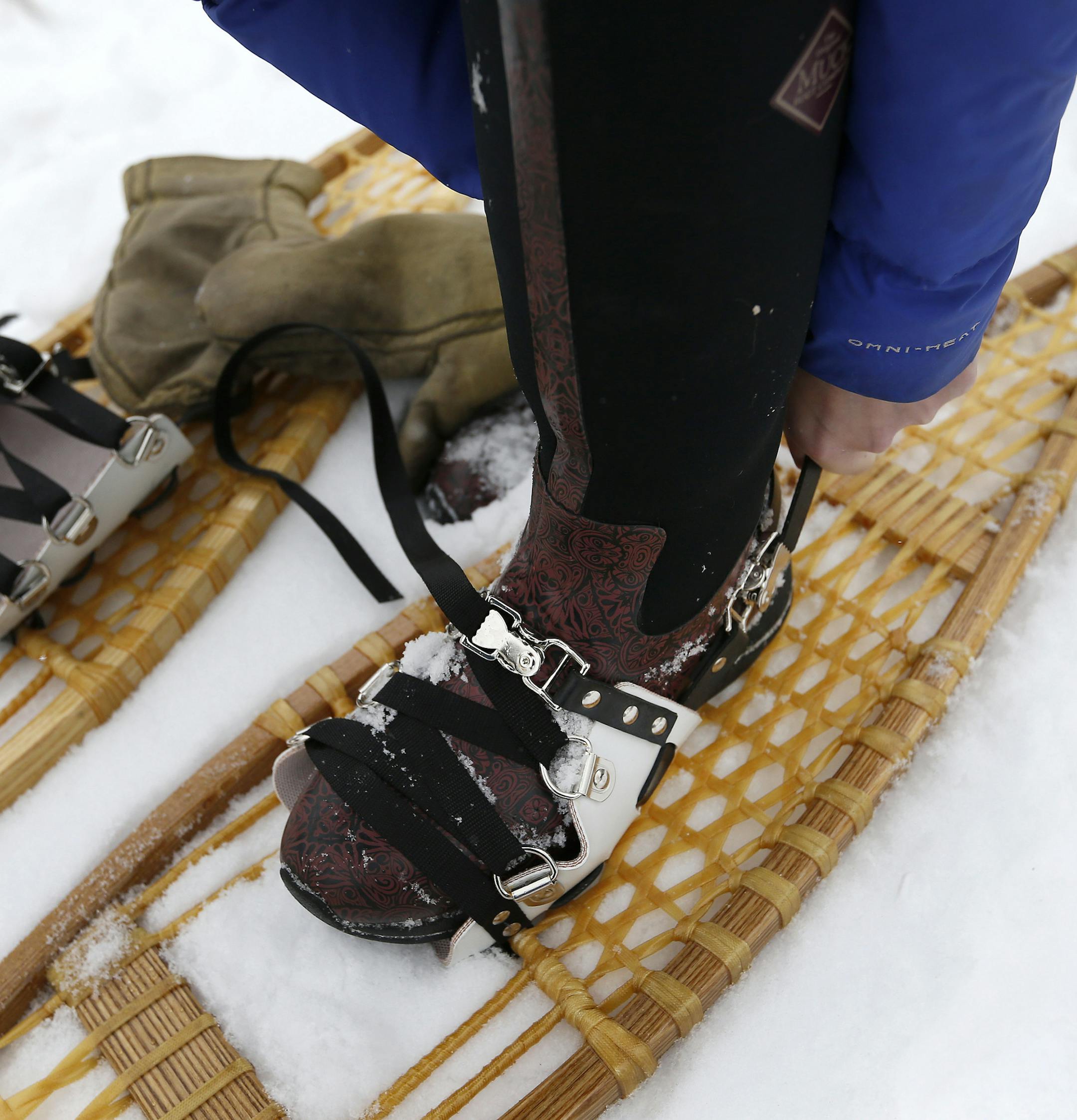 Lacing up a pair of traditional webbed snowshoes.