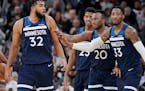 The Timberwolves' Karl-Anthony Towns reacts after being called for a technical foul as he is led away from a referee by teammates Robert Covington (33