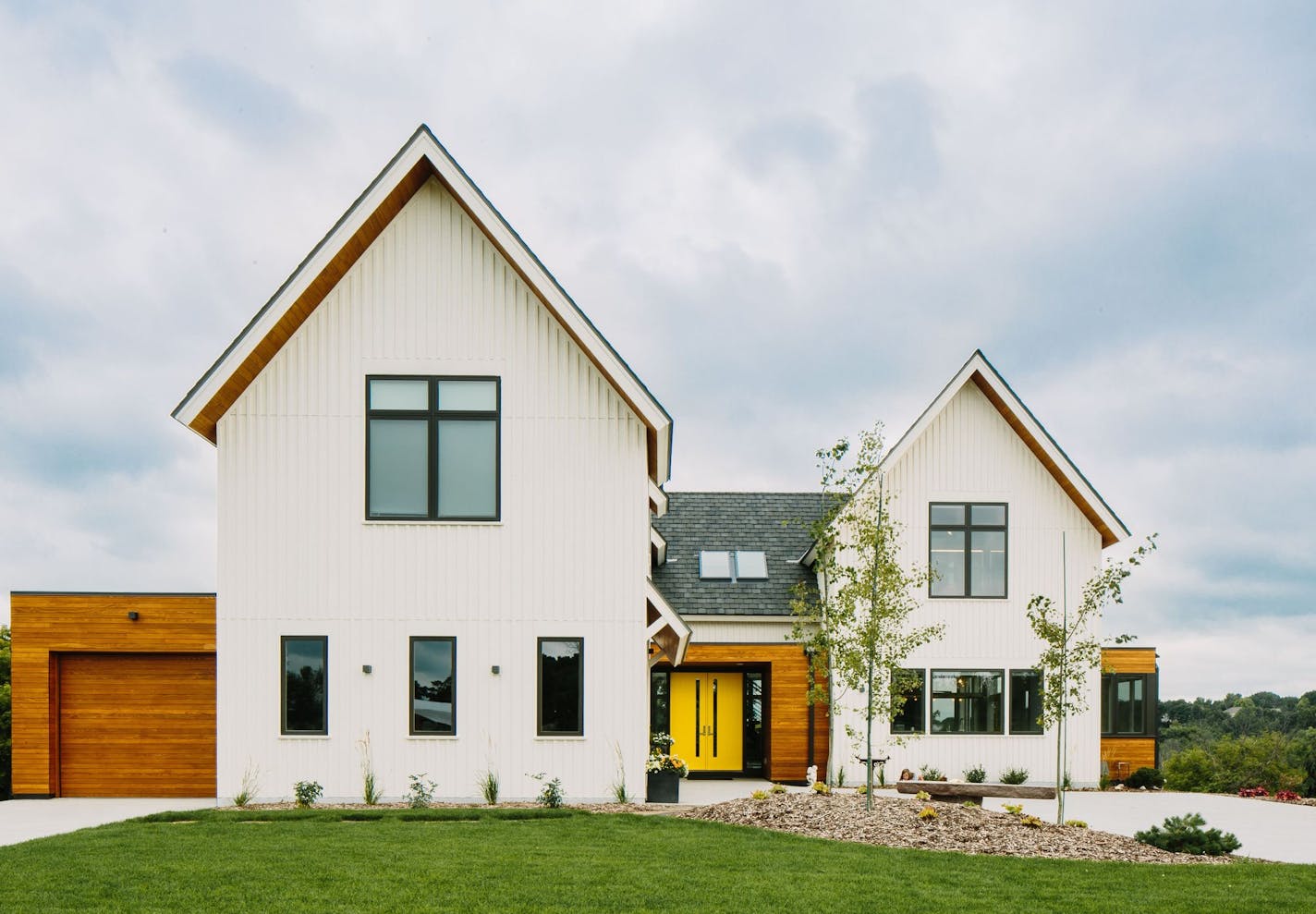 The modern farmhouse marries traditional gables with flat-roof forms, with a nod to vibrant midcentury color.