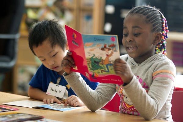 Kindergartners Jacky Vang, left, and Precious Garwoloquoi read books Thursday at Earle Brown Elementary School in Brooklyn Center.