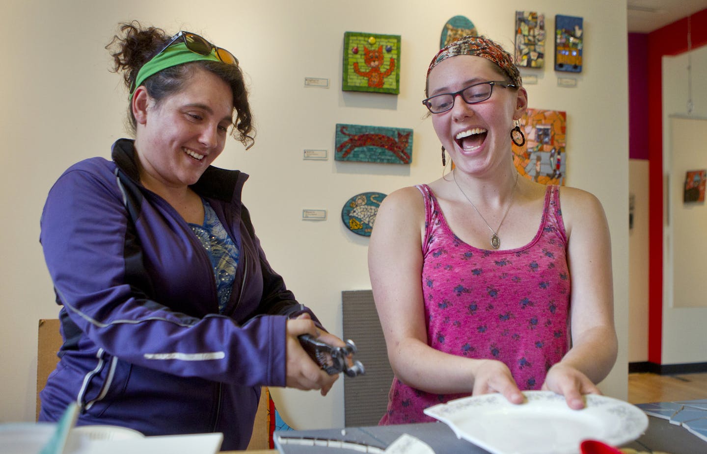 Adrienne Sherman, right, of Roseville, laughed as her friend, Maddie Maney, of Minneapolis, nervously cut a plate for the first time during free studio time at Mosaic On A Stick, a mosaic supply store, in St. Paul. The owner, Lori Greene, moved into the historic Clarence Wigington building in Hamline Park about two months ago.