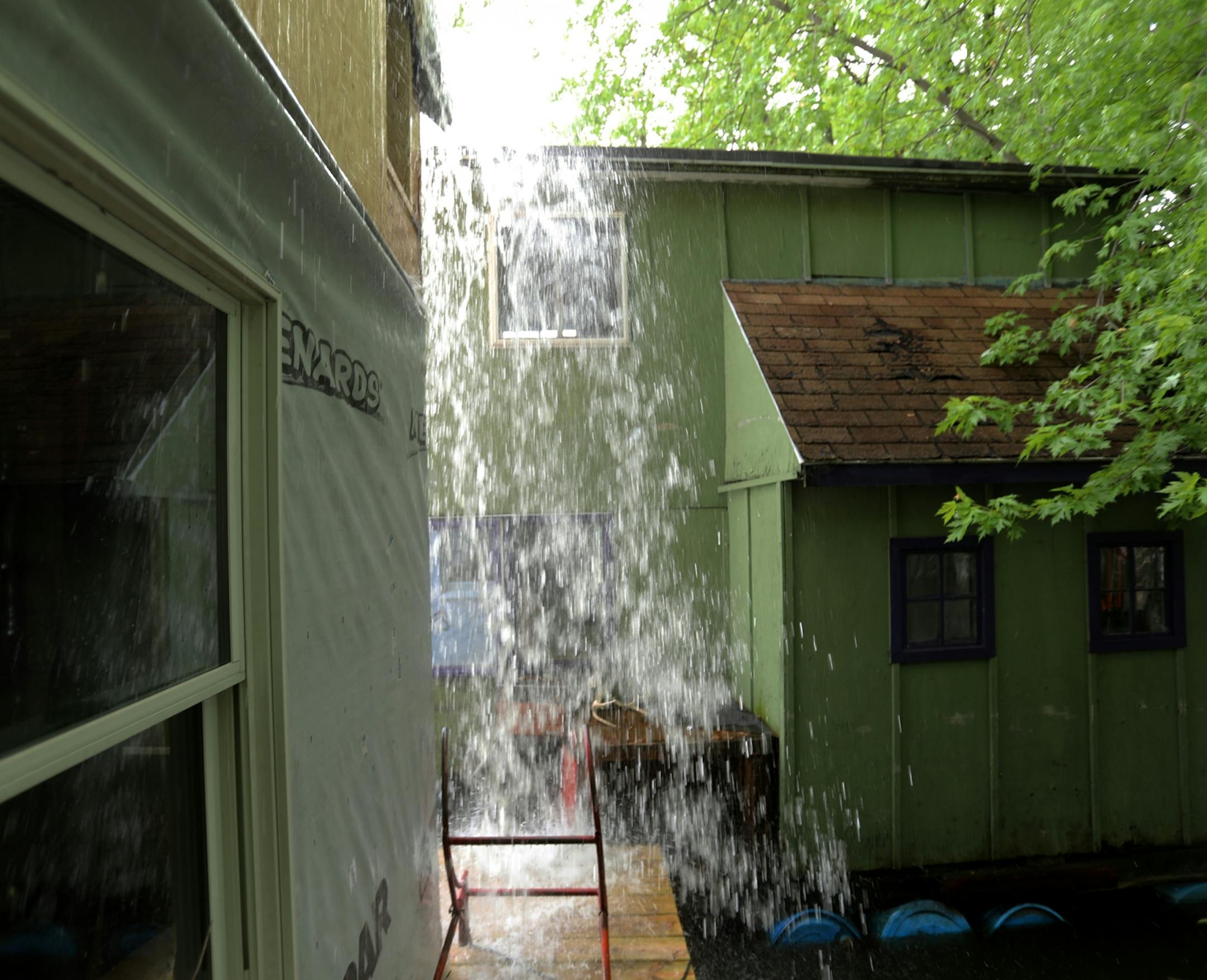 Rain that accumulated on a temporary tarp roof on Moses Simon's unfinished boathouse falls to the ground as Simon drained it in Winona.
