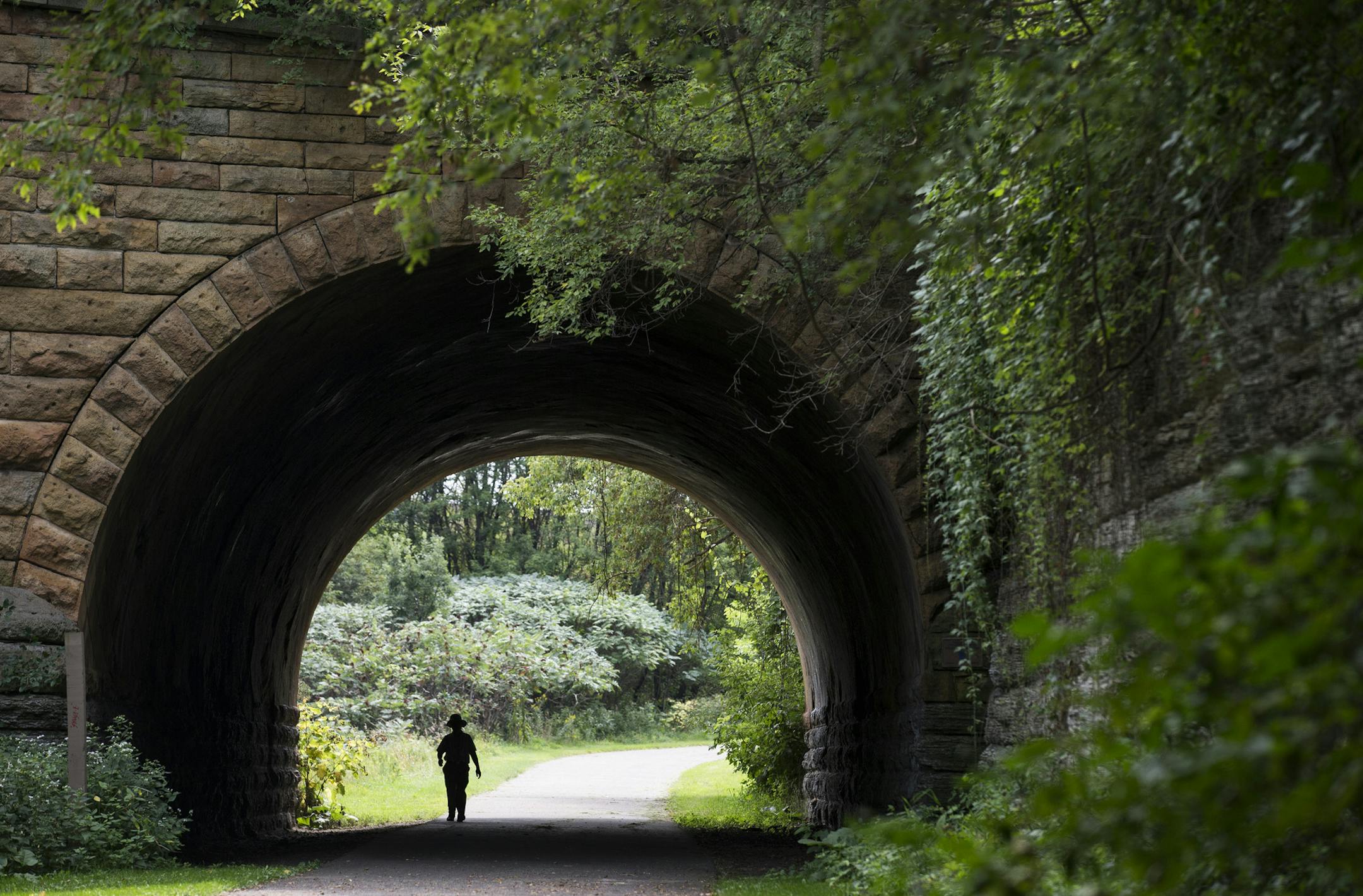 A walker passes under the 7th Street bridge in Swede Hollow Park in St. Paul on Friday, August 28, 2015. ] LEILA NAVIDI leila.navidi@startribune.com / BACKGROUND INFORMATION: Community activists fear that plans for a new rapid busway or train from Forest Lake to Union Depot in downtown St. Paul could ruin Swede Hollow Park.