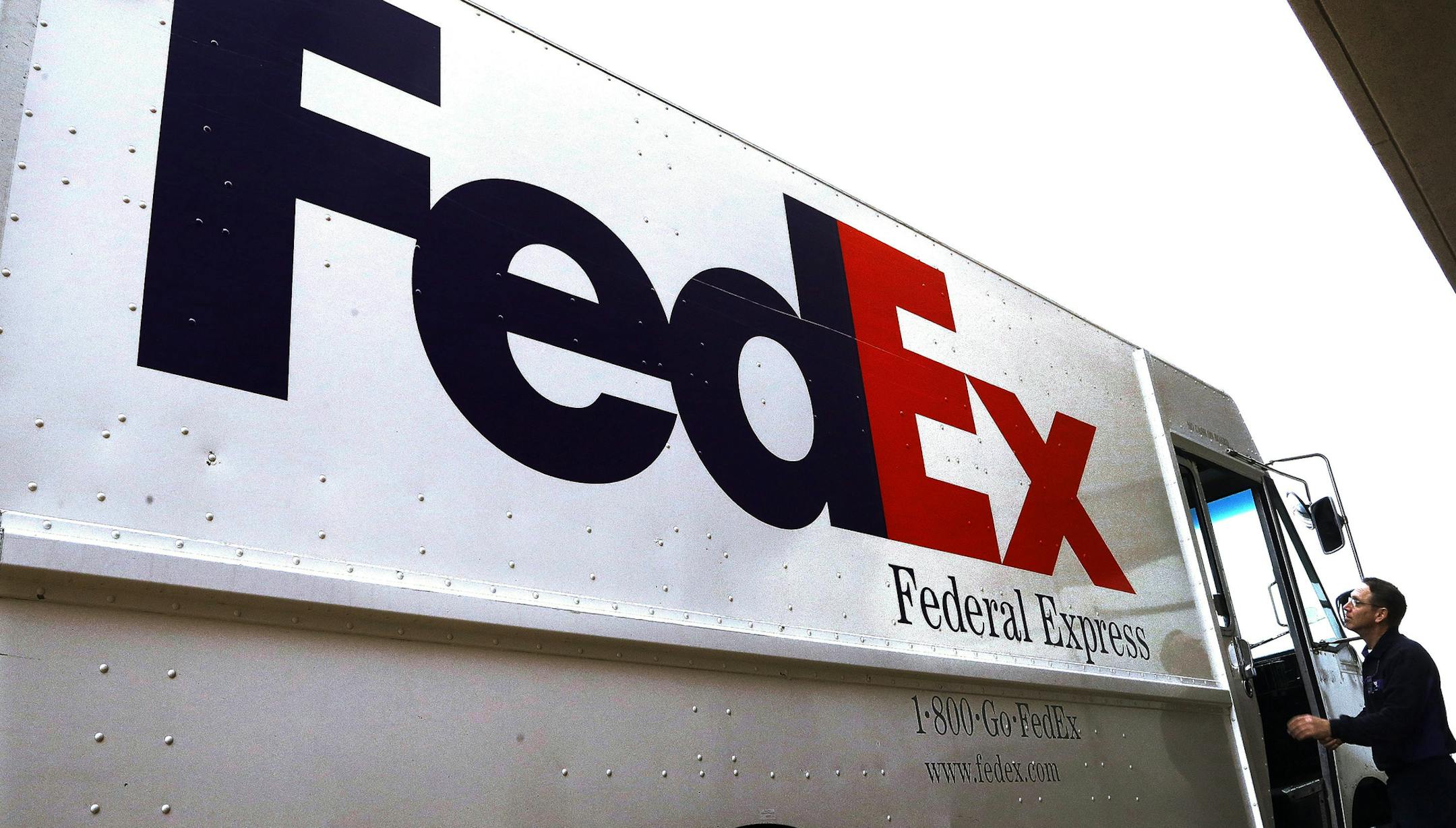 FILE - In this Dec. 18, 2014 file photo, a Federal Express driver returns to his truck after delivering a package to a business in Springfield, Ill. FedEx earned $1.25 billion in its latest quarter, as online shopping remained popular among customers avoiding stores and shipments between businesses improved. The delivery giant reported Tuesday, Sept. 15, 2020 that it brought in $19.3 billion in revenue during the three months that ended Aug. 31, FedEx's fiscal first quarter. (AP Photo/Seth Perlm
