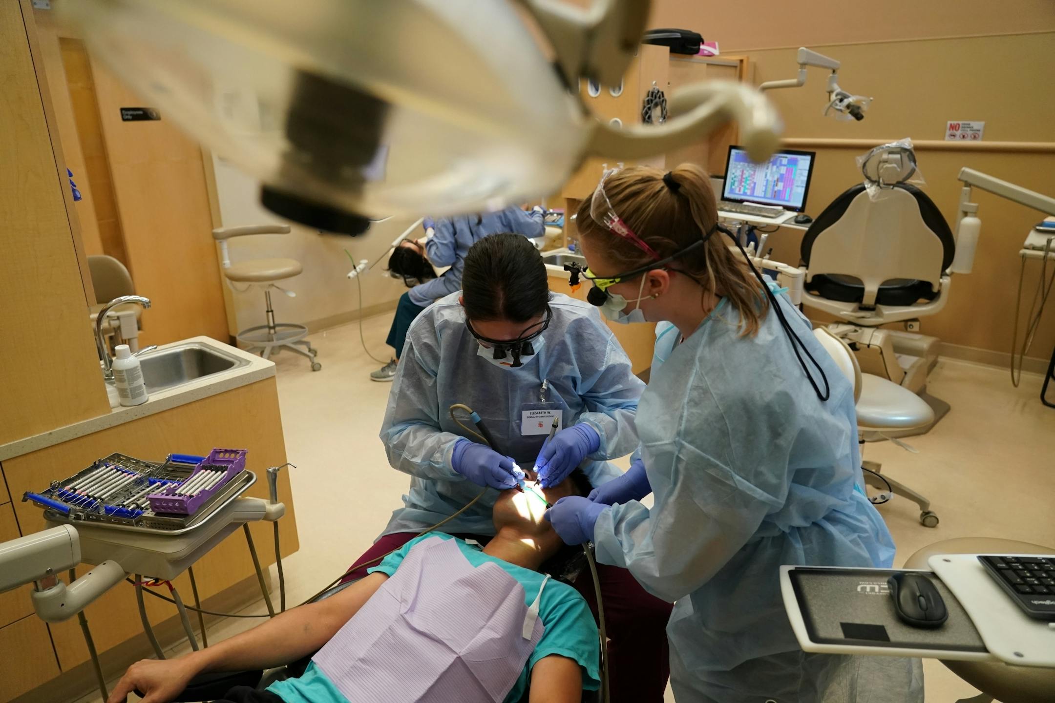 Second year dental students Elizabeth Wilder (left) and Katherine Rolek gave Mow Ning of St. Paul dental care inside Community Dental Care in Maplewood. The two students were part of a group of 35 who continued their education and training through Century College after the abrupt closing of Argosy Univeristy.