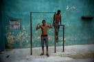 A young man strikes a pose showing off his muscles, framed by a pull up bar in Havana, Cuba, Wednesday, Feb. 5, 2020. (AP Photo/Ramon Espinosa)