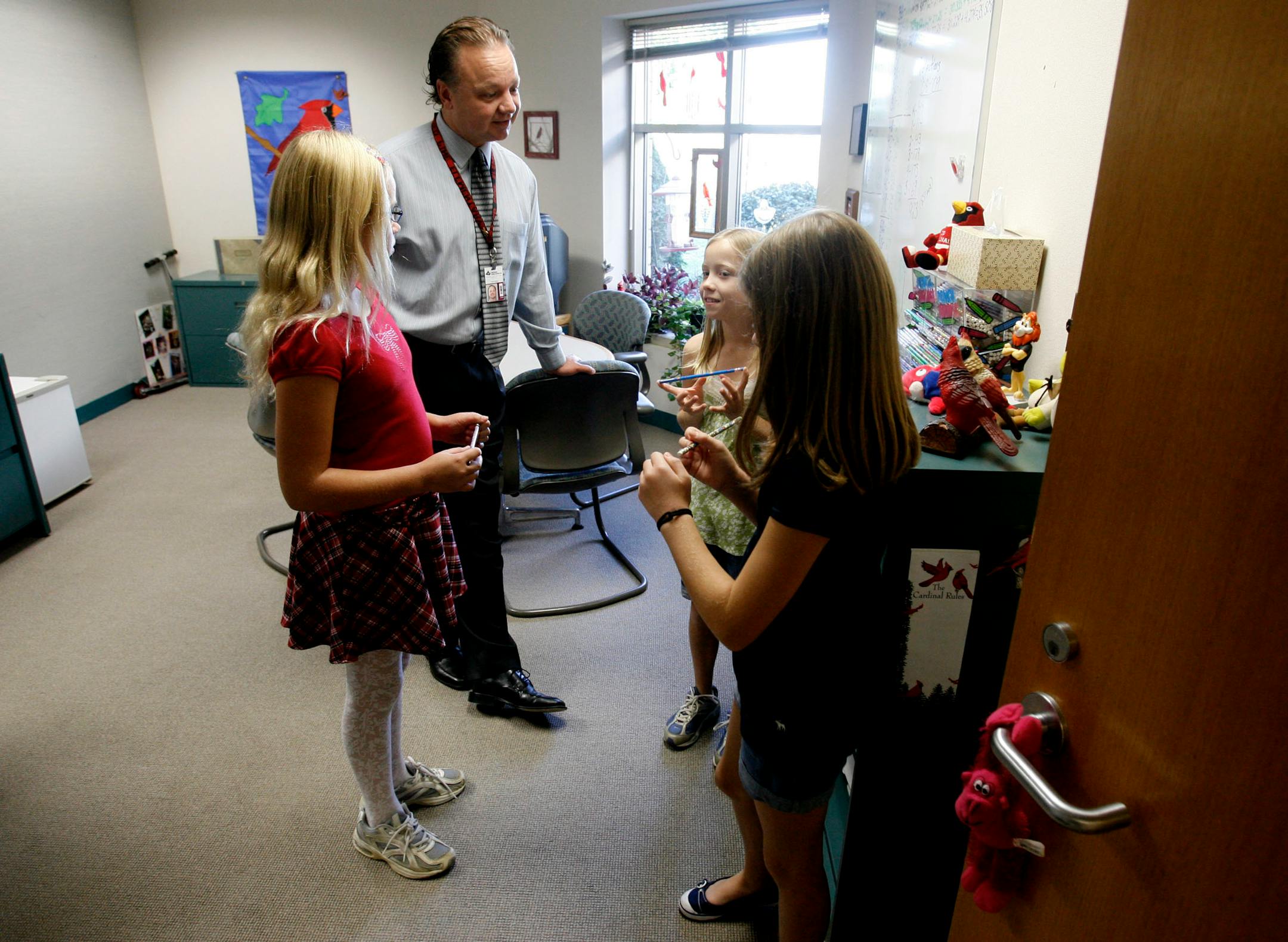 From left, Elicia Osland, 10, and twin sisters Emily and Madison Sides, 10, got pencils from a special dispenser in the office of Red Pine Elementary Principal Gary Anger. Red Pine is one of several schools that have banned or severely limited birthday treats, citing concern about student health and wellness.