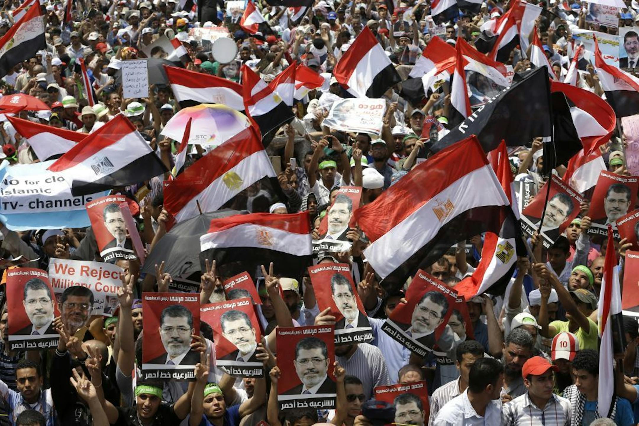 Supporters of Egypt's ousted President Mohammed Morsi, wave Egyptian flags and hold portraits of Morsi with Arabic words that read:"Mohammed Morsi, legitimacy red line," during demonstration at Nasr city, Cairo, Egypt, Friday, July 12, 2013. Thousands of supporters of Egypt�s Muslim Brotherhood group rallied in a Cairo city square, waving pictures of the ousted President Mohammed Morsi and chanting anti-military slogans, deriding army chief who led Morsi�s removal as �traitor� with one ultracons