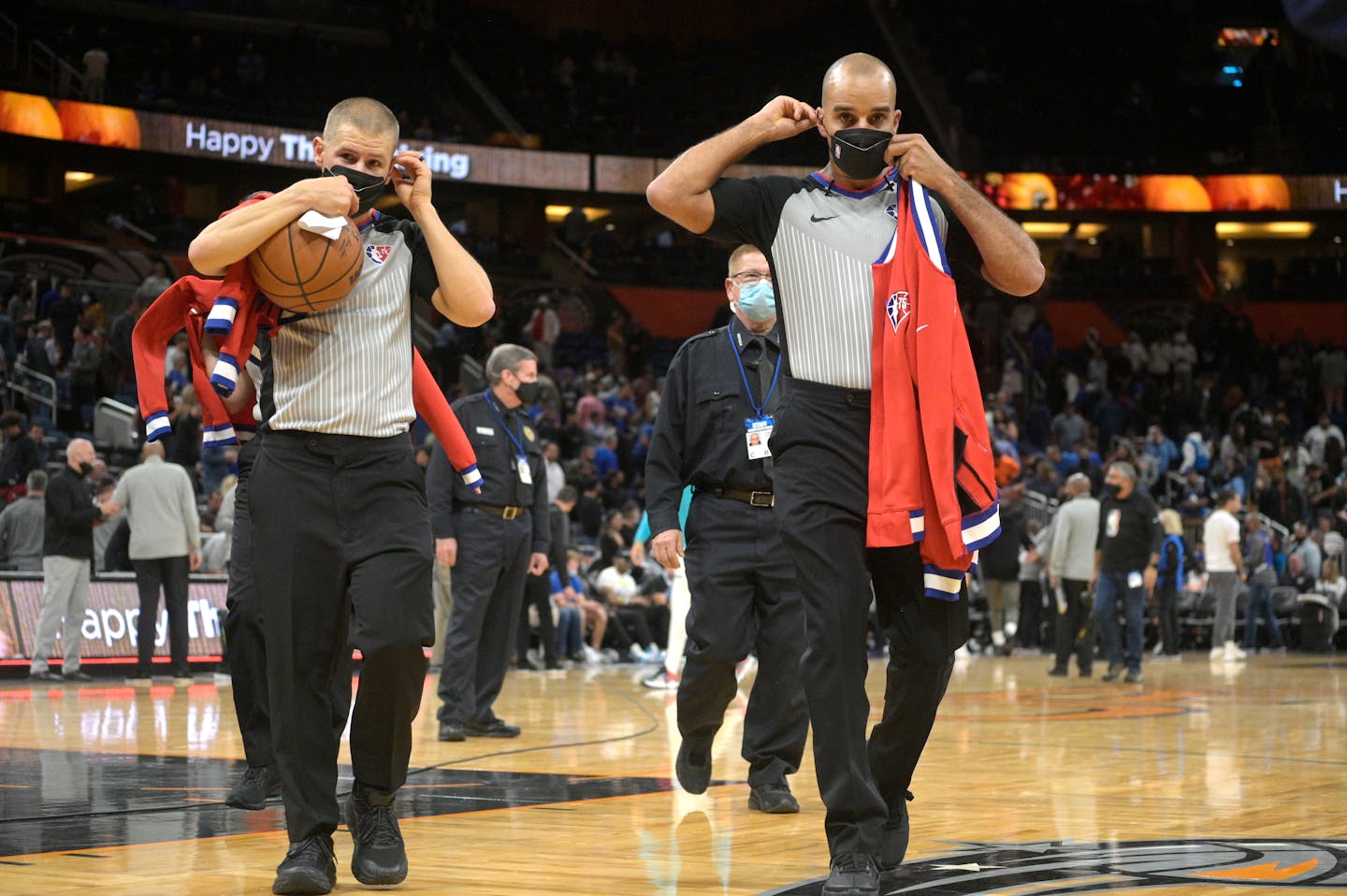 Officials Tyler Ford, left, and Matt Myers wear face masks to help curb the spread of COVID-19 while leaving the court after an NBA basketball game between the Orlando Magic and the Charlotte Hornets, Wednesday, Nov. 24, 2021, in Orlando, Fla. (AP Photo/Phelan M. Ebenhack)