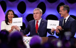 International Olympic Committee President Thomas Bach, center, poses for photos with Anne Hidalgo, left, Mayor of Paris, and Eric Garcetti, Mayor of L